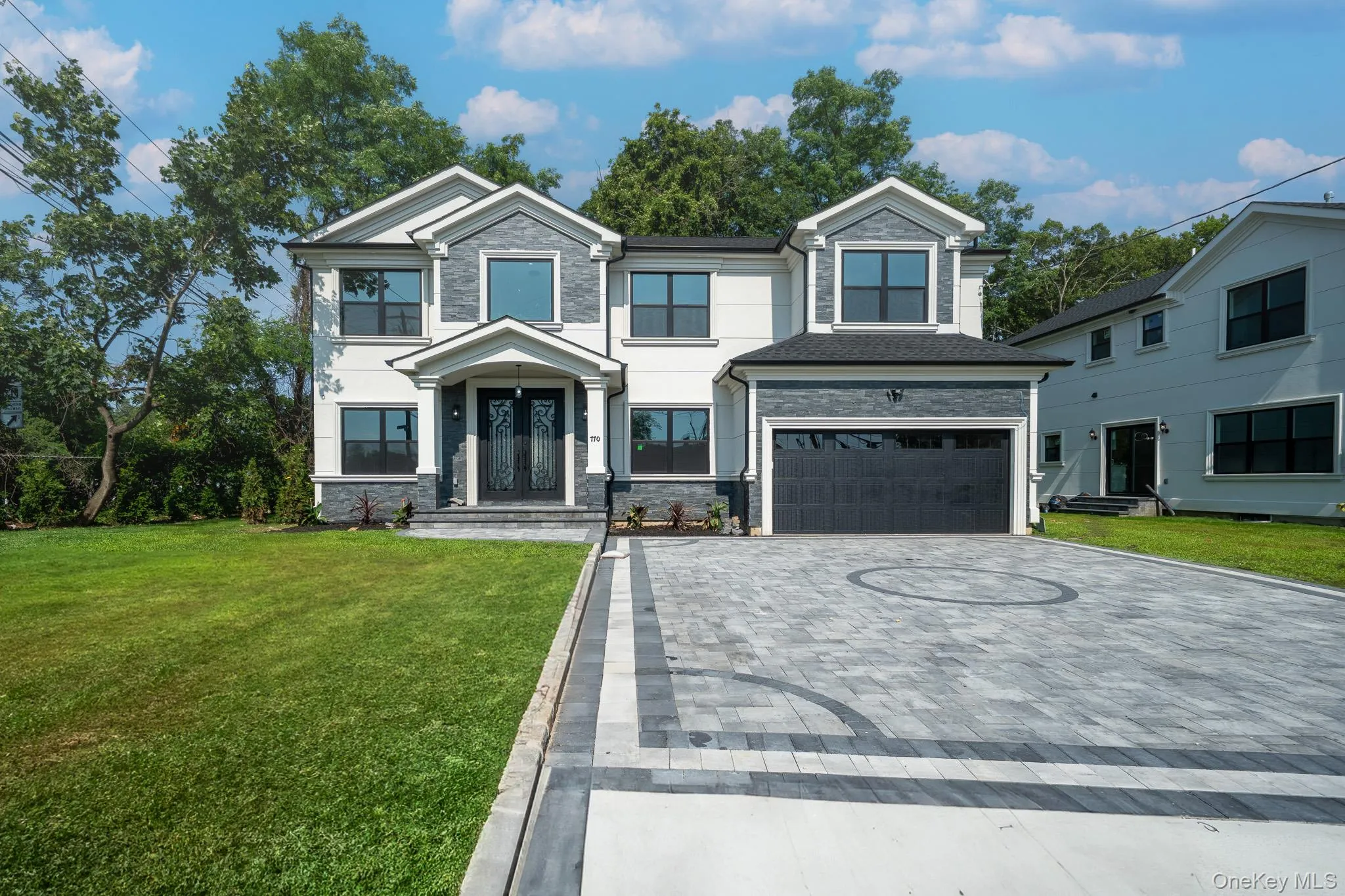 View of front of property featuring decorative driveway, a garage, stone siding, and a front yard View of front of property featuring decorative driveway, a garage, stone siding, and a front yard
