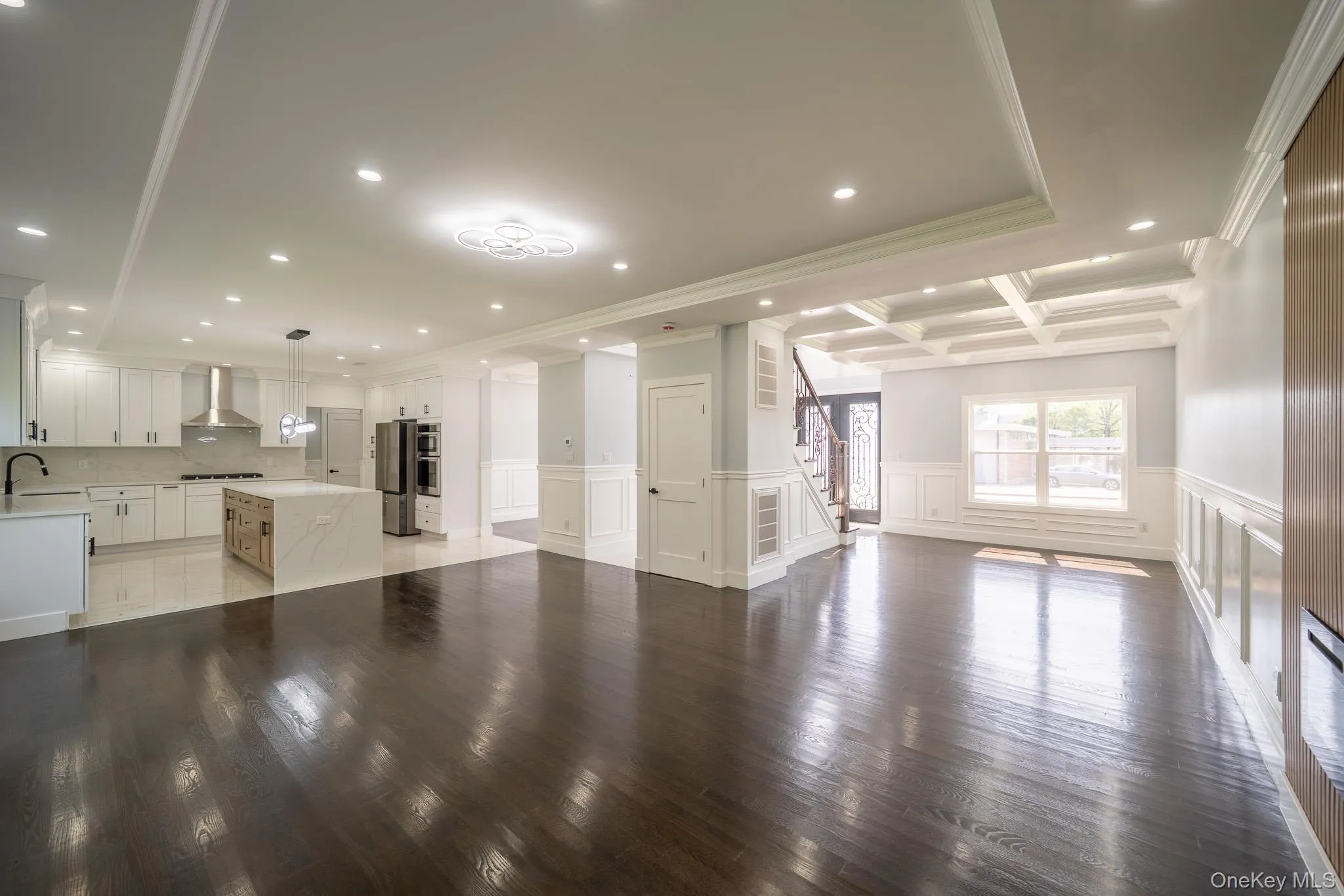 Unfurnished living room with recessed lighting, a decorative wall, wainscoting, coffered ceiling, and crown molding Unfurnished living room with recessed lighting, a decorative wall, wainscoting, coffered ceiling, and crown molding