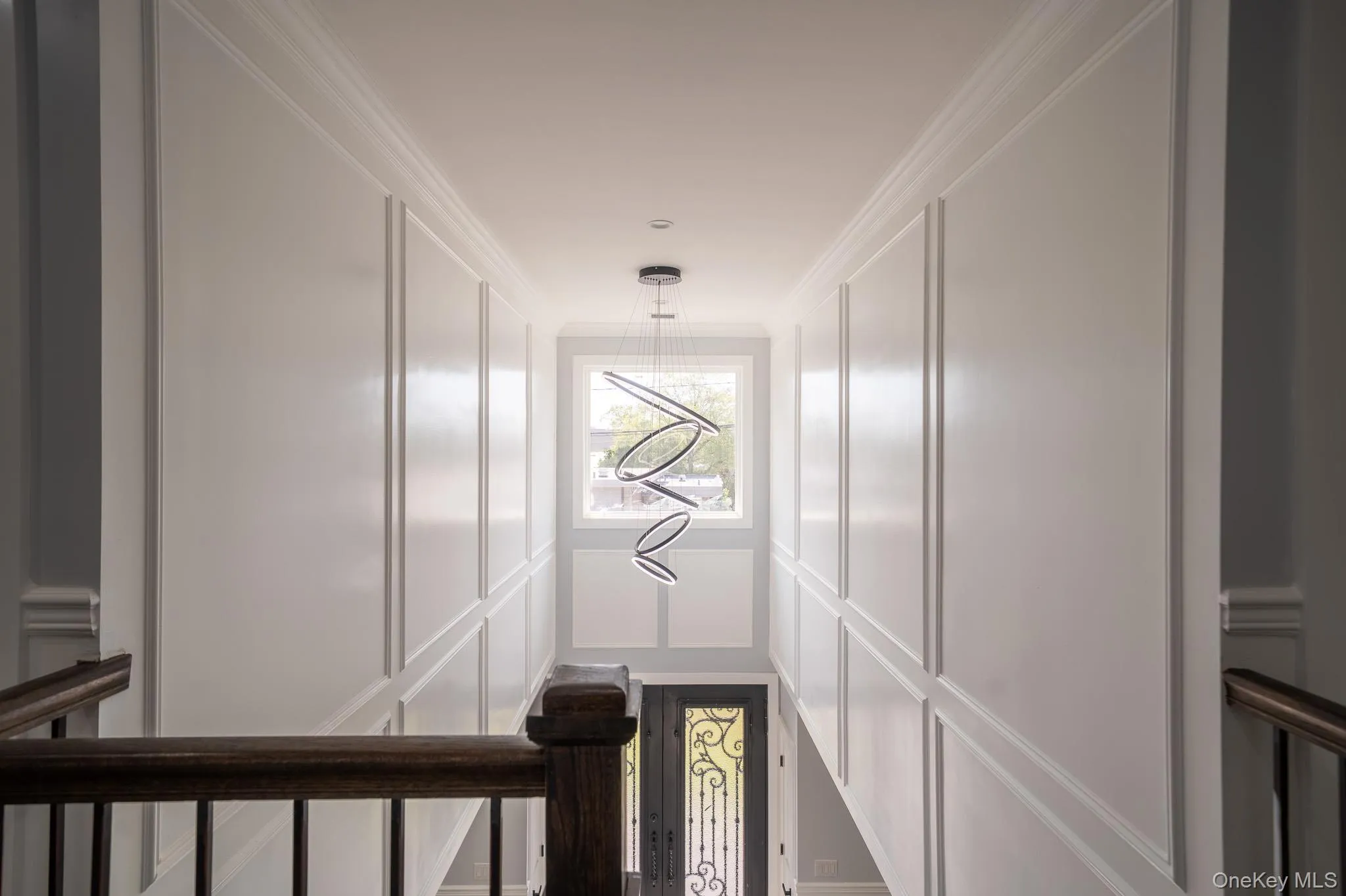 Hallway with crown molding, a decorative wall, and a chandelier Hallway with crown molding, a decorative wall, and a chandelier