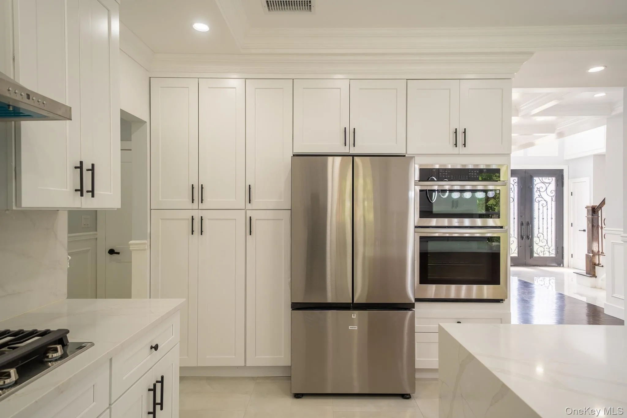 Kitchen with recessed lighting, stainless steel appliances, crown molding, white cabinets, and light stone counters Kitchen with recessed lighting, stainless steel appliances, crown molding, white cabinets, and light stone counters
