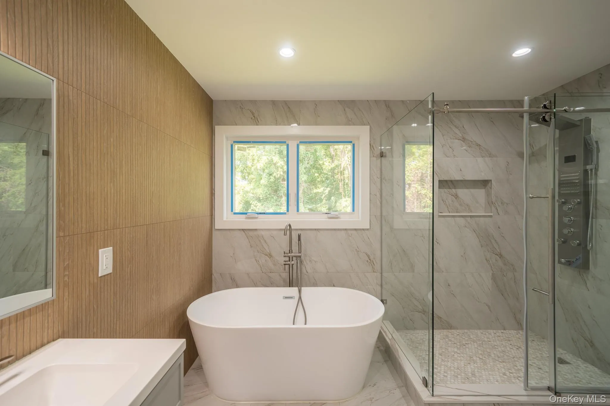 Bathroom with tile walls, vanity, a marble finish shower, a freestanding bath, and marble tiled flooring Bathroom with tile walls, vanity, a marble finish shower, a freestanding bath, and marble tiled flooring