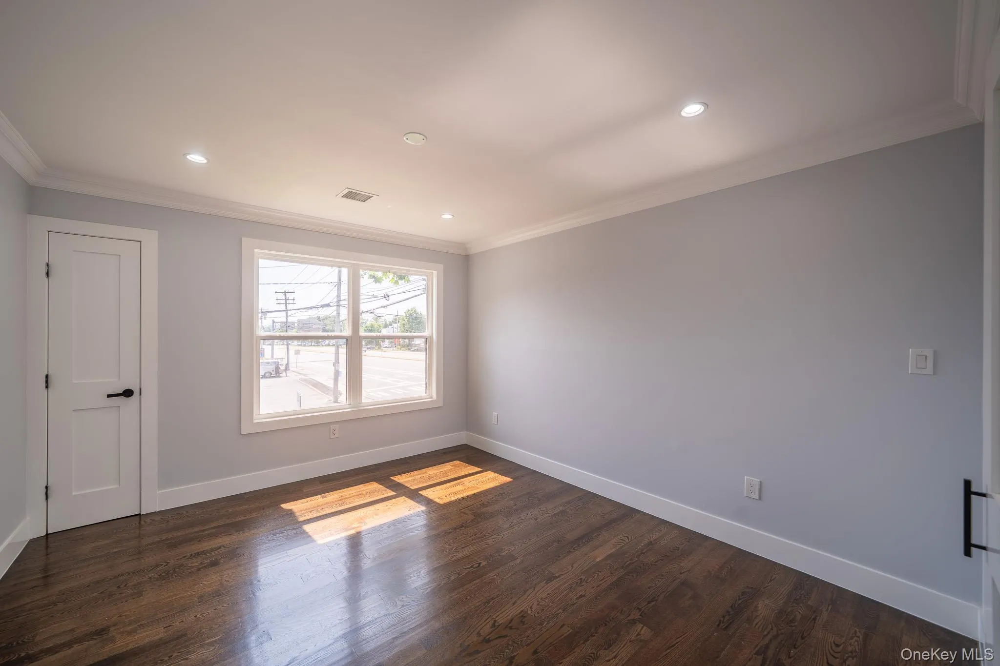 Spare room with dark wood-style flooring, crown molding, and recessed lighting Spare room with dark wood-style flooring, crown molding, and recessed lighting