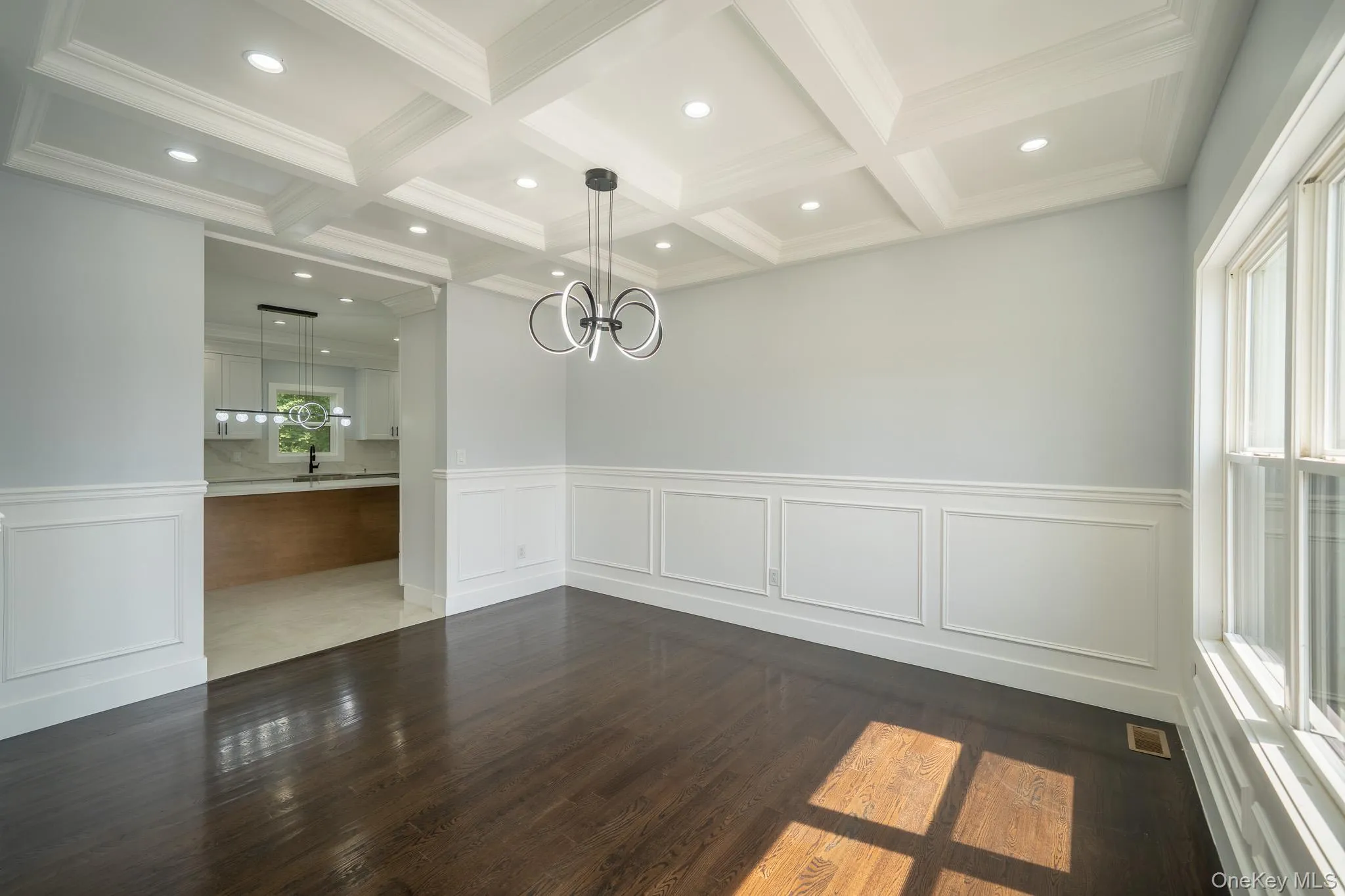 Unfurnished dining area with a decorative wall, a wainscoted wall, dark wood finished floors, and a chandelier Unfurnished dining area with a decorative wall, a wainscoted wall, dark wood finished floors, and a chandelier