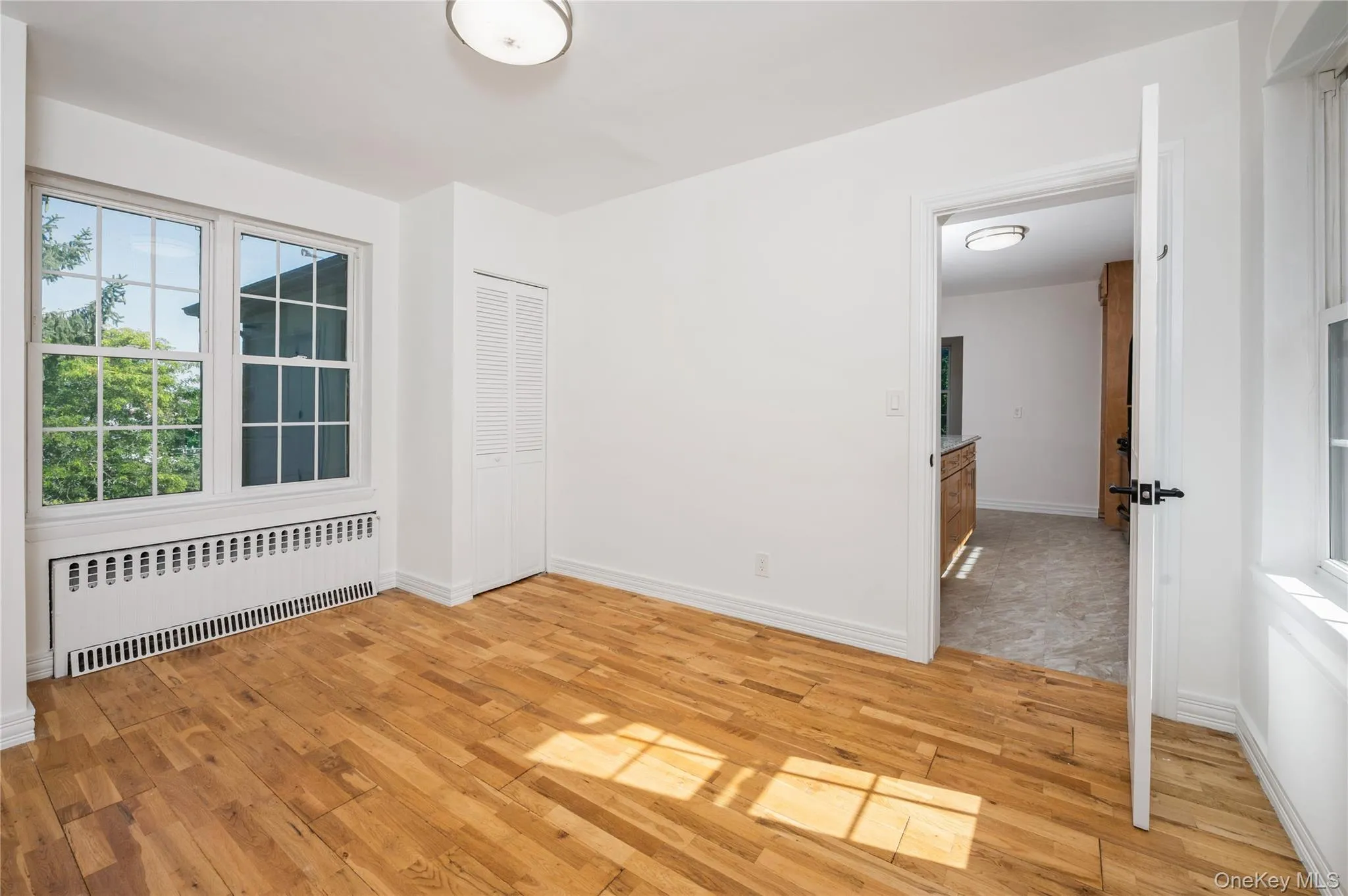 Empty room with light wood-style floors and radiator heating unit Empty room with light wood-style floors and radiator heating unit