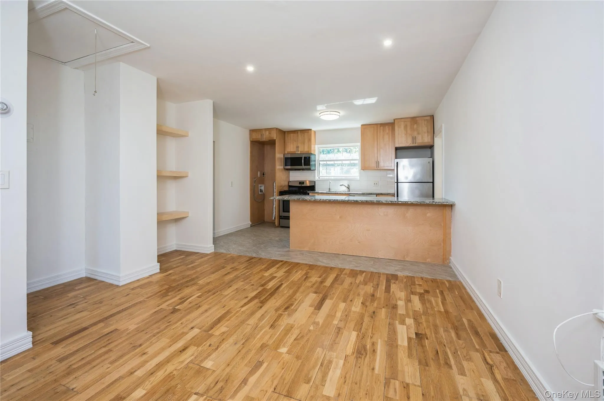 Kitchen with a peninsula, light wood-type flooring, appliances with stainless steel finishes, decorative backsplash, and dark stone counters Kitchen with a peninsula, light wood-type flooring, appliances with stainless steel finishes, decorative backsplash, and dark stone counters