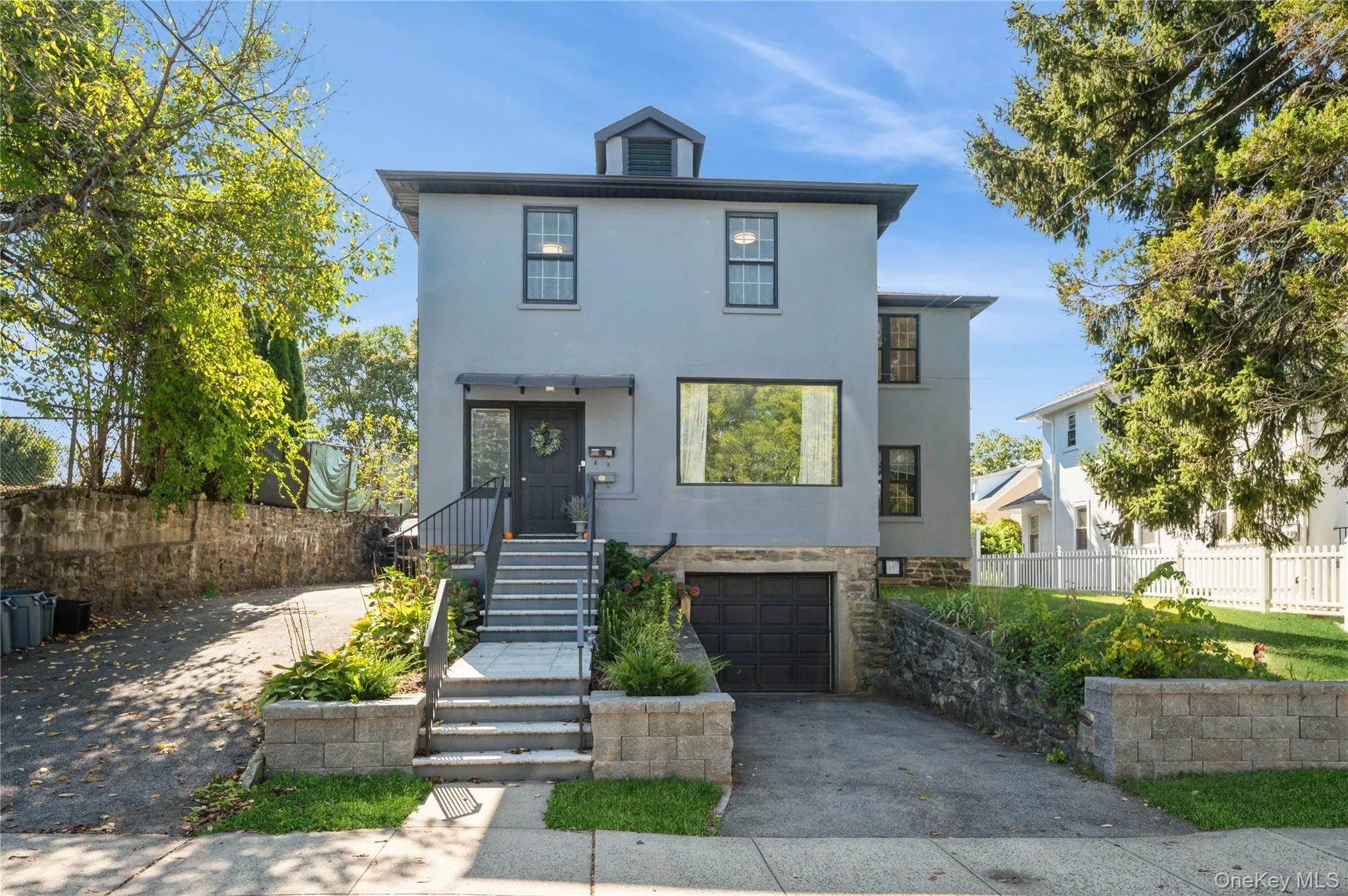 View of front of property with concrete driveway, stucco siding, stone siding, and an attached garage View of front of property with concrete driveway, stucco siding, stone siding, and an attached garage