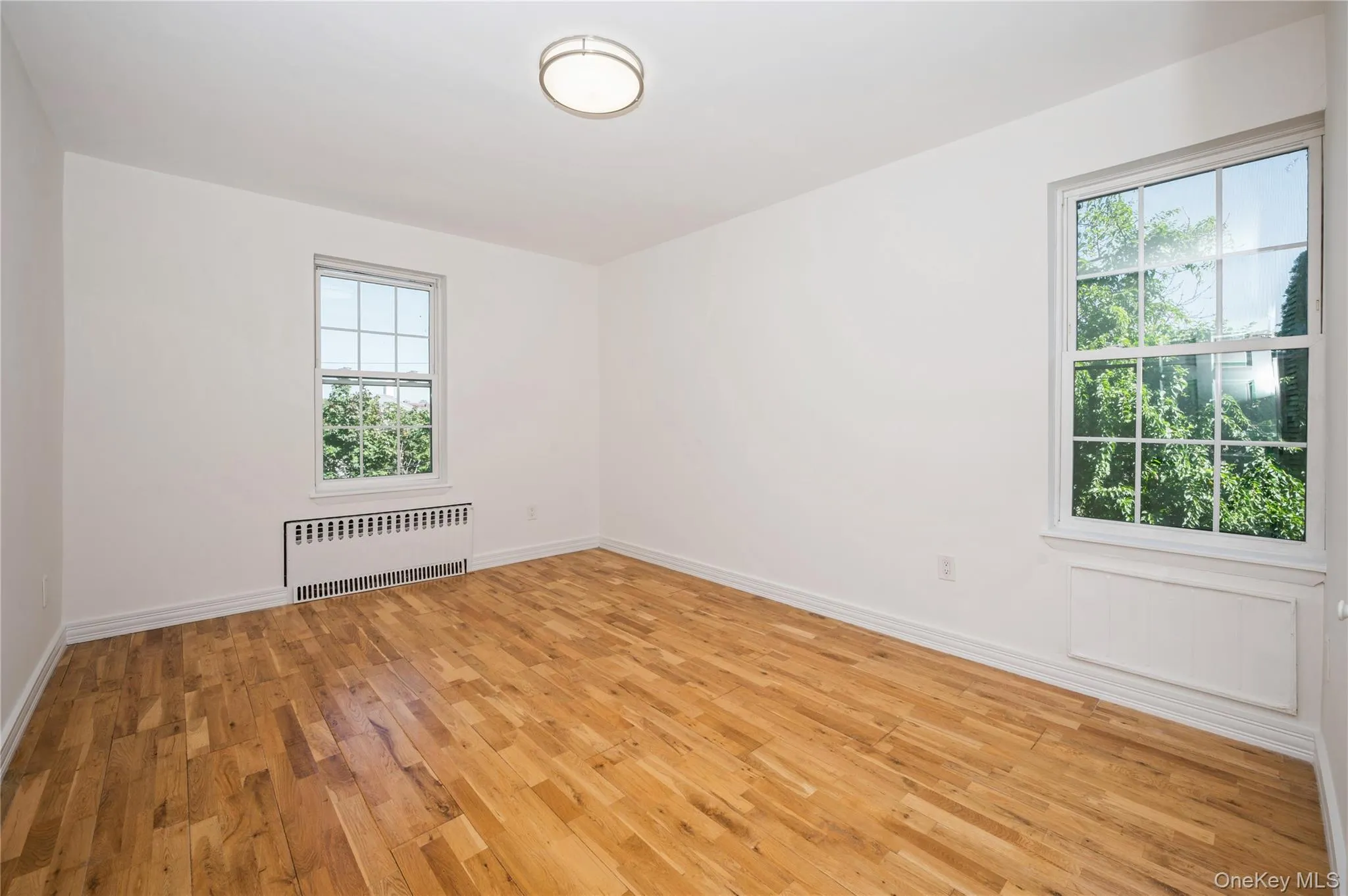 Unfurnished room with radiator and light wood-style flooring Unfurnished room with radiator and light wood-style flooring