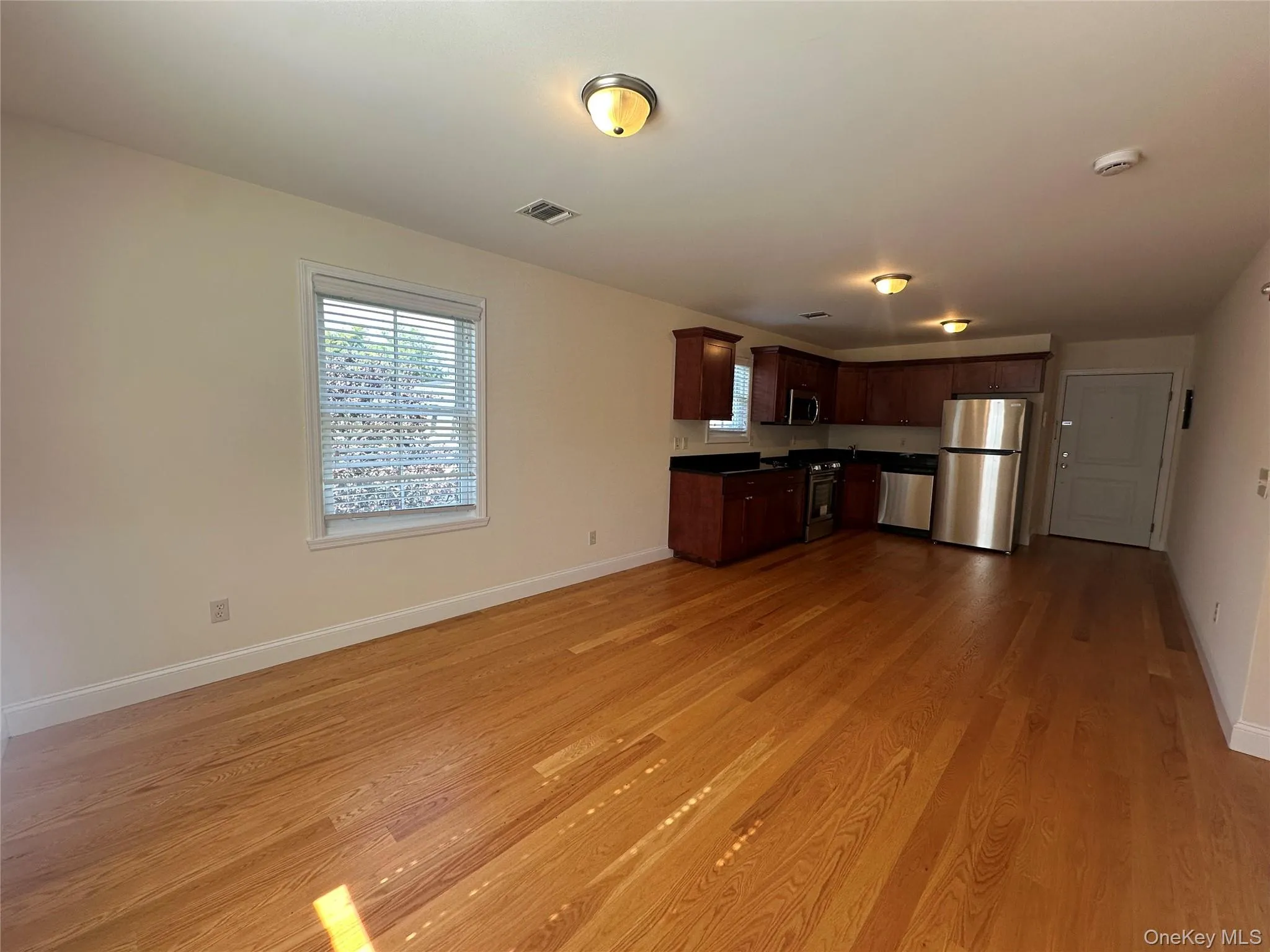 Kitchen with dark countertops, appliances with stainless steel finishes, open floor plan, light wood finished floors, and dark brown cabinetry Kitchen with dark countertops, appliances with stainless steel finishes, open floor plan, light wood finished floors, and dark brown cabinetry