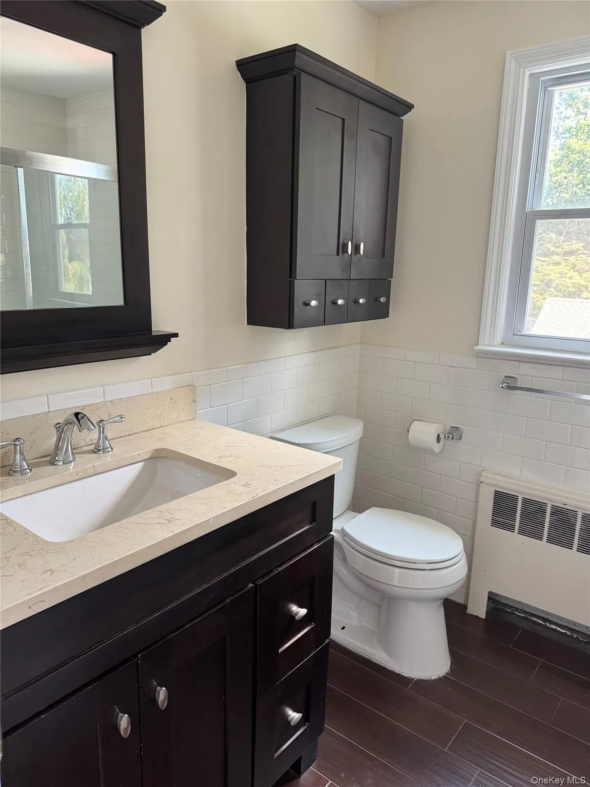 Bathroom featuring radiator, vanity, tile walls, wood tiled floors, and a shower with door Bathroom featuring radiator, vanity, tile walls, wood tiled floors, and a shower with door