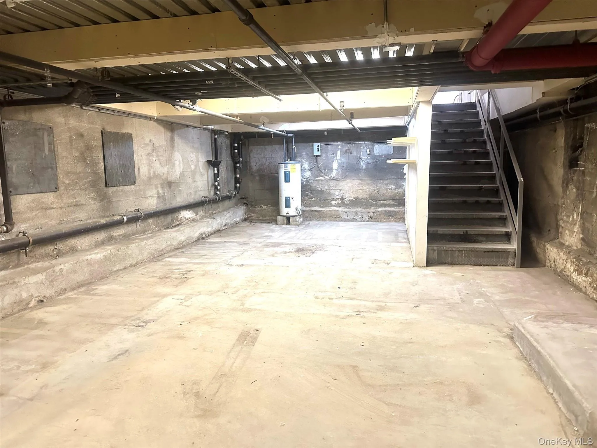 Unfinished basement featuring stairs and water heater Unfinished basement featuring stairs and water heater