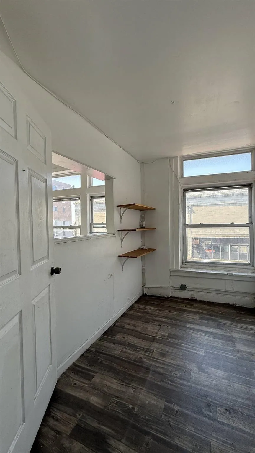 Spare room with healthy amount of natural light and dark wood-style flooring Spare room with healthy amount of natural light and dark wood-style flooring