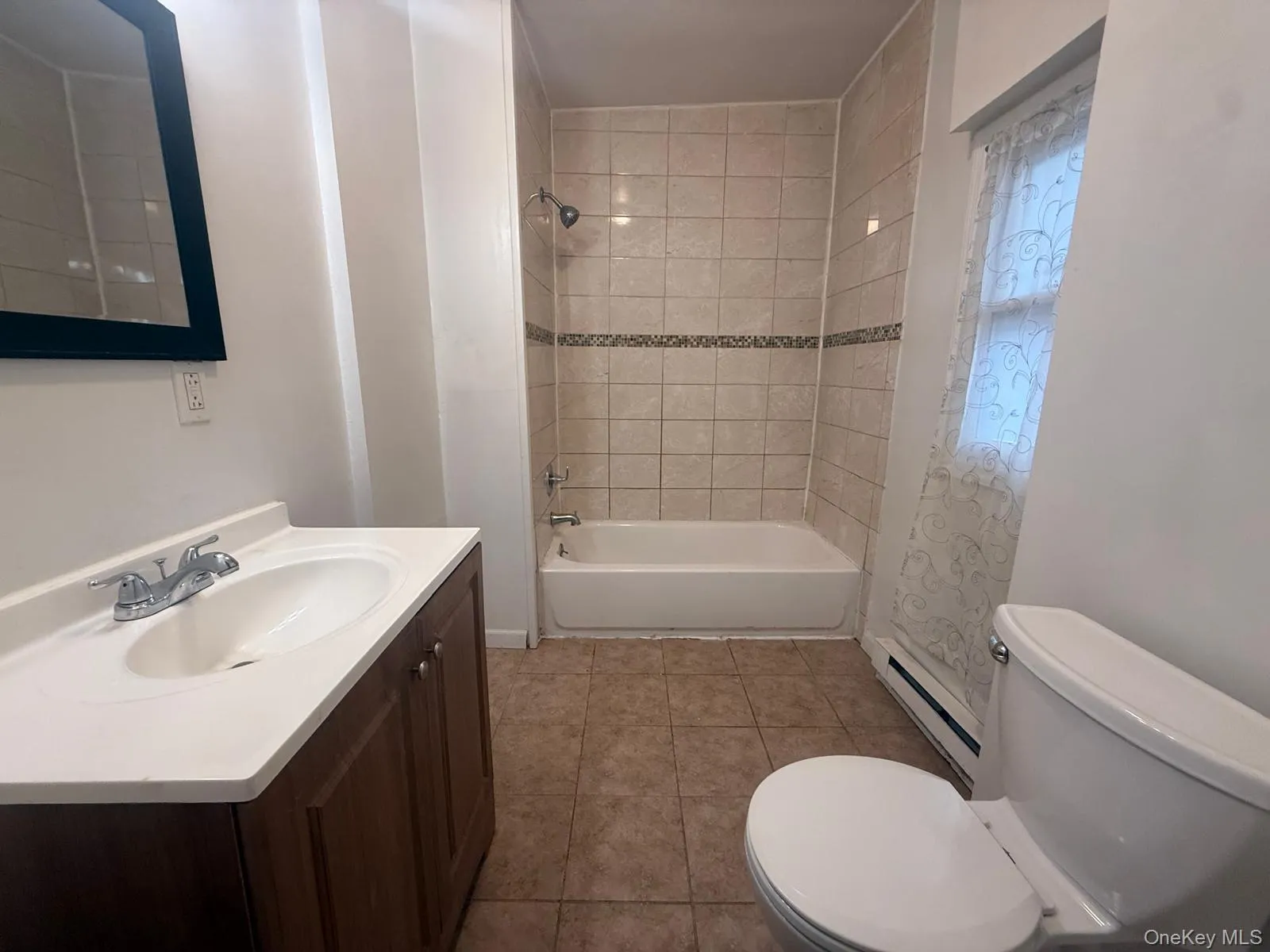 Bathroom with a baseboard heating unit, light tile patterned flooring, vanity, and bathing tub / shower combination Bathroom with a baseboard heating unit, light tile patterned flooring, vanity, and bathing tub / shower combination