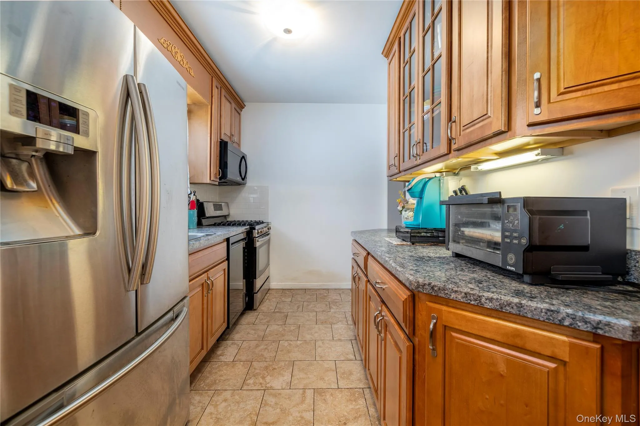 EAT IN Kitchen with appliances with stainless steel finishes, brown cabinetry, and glass insert cabinets EAT IN Kitchen with appliances with stainless steel finishes, brown cabinetry, and glass insert cabinets