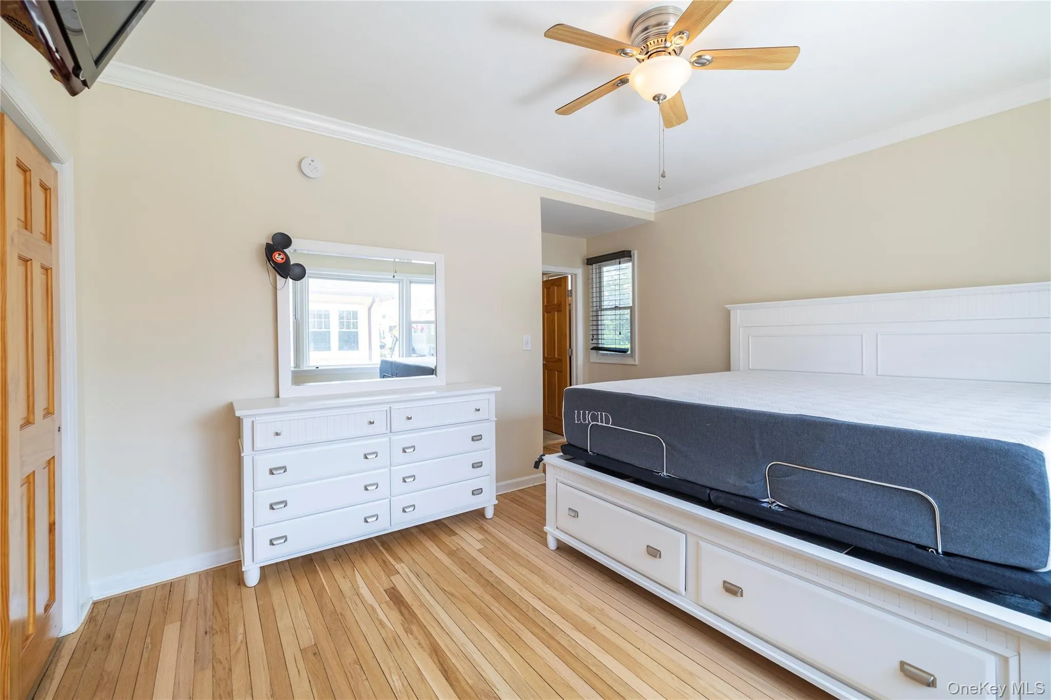 Bedroom featuring crown molding, light wood-style floors, and a ceiling fan Bedroom featuring crown molding, light wood-style floors, and a ceiling fan
