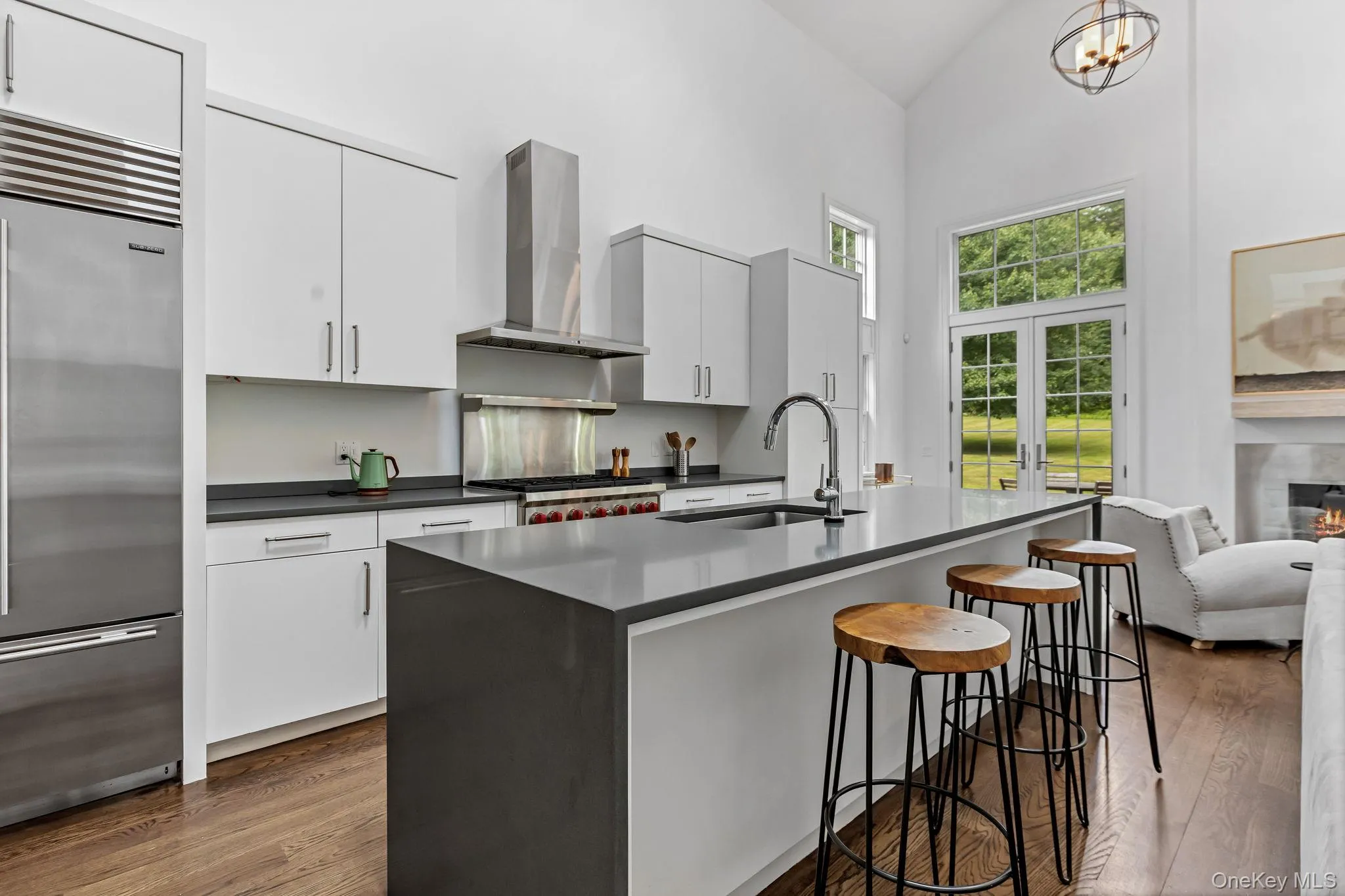 Kitchen featuring vaulted ceiling, Sub Zero refrigerator, dark countertops, exhaust hood, and a kitchen breakfast bar Kitchen featuring vaulted ceiling, Sub Zero refrigerator, dark countertops, exhaust hood, and a kitchen breakfast bar