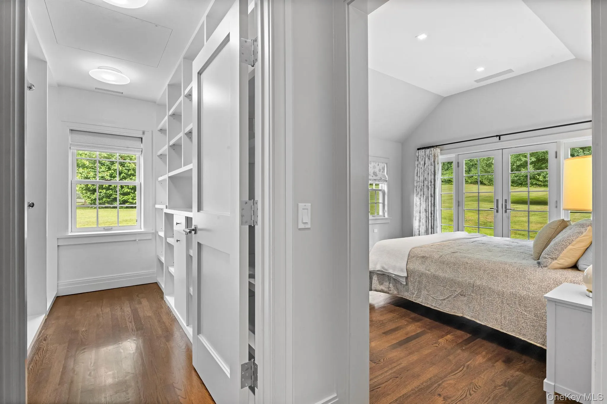 Bedroom with wood floors, french doors, vaulted ceiling, and walk-in closet. Bedroom with wood floors, french doors, vaulted ceiling, and walk-in closet.