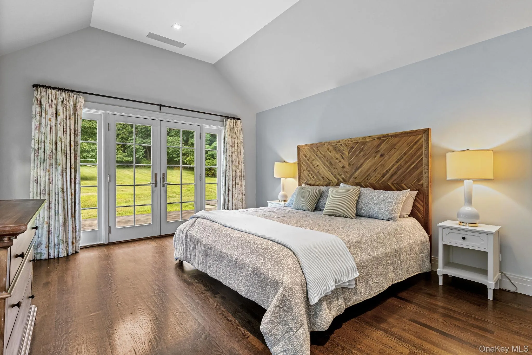 1st floor Primary Suite with vaulted ceiling, access to exterior via french doors, wood floors, and walk-in closet 1st floor Primary Suite with vaulted ceiling, access to exterior via french doors, wood floors, and walk-in closet