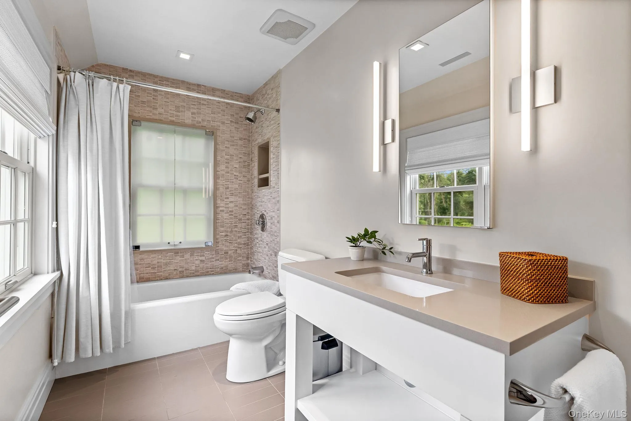 1st floor full bathroom off of family room/home office/or bedroom flexible space featuring shower / bathtub combination with curtain, tile floors, vanity, and plenty of natural light. 1st floor full bathroom off of family room/home office/or bedroom flexible space featuring shower / bathtub combination with curtain, tile floors, vanity, and plenty of natural light.