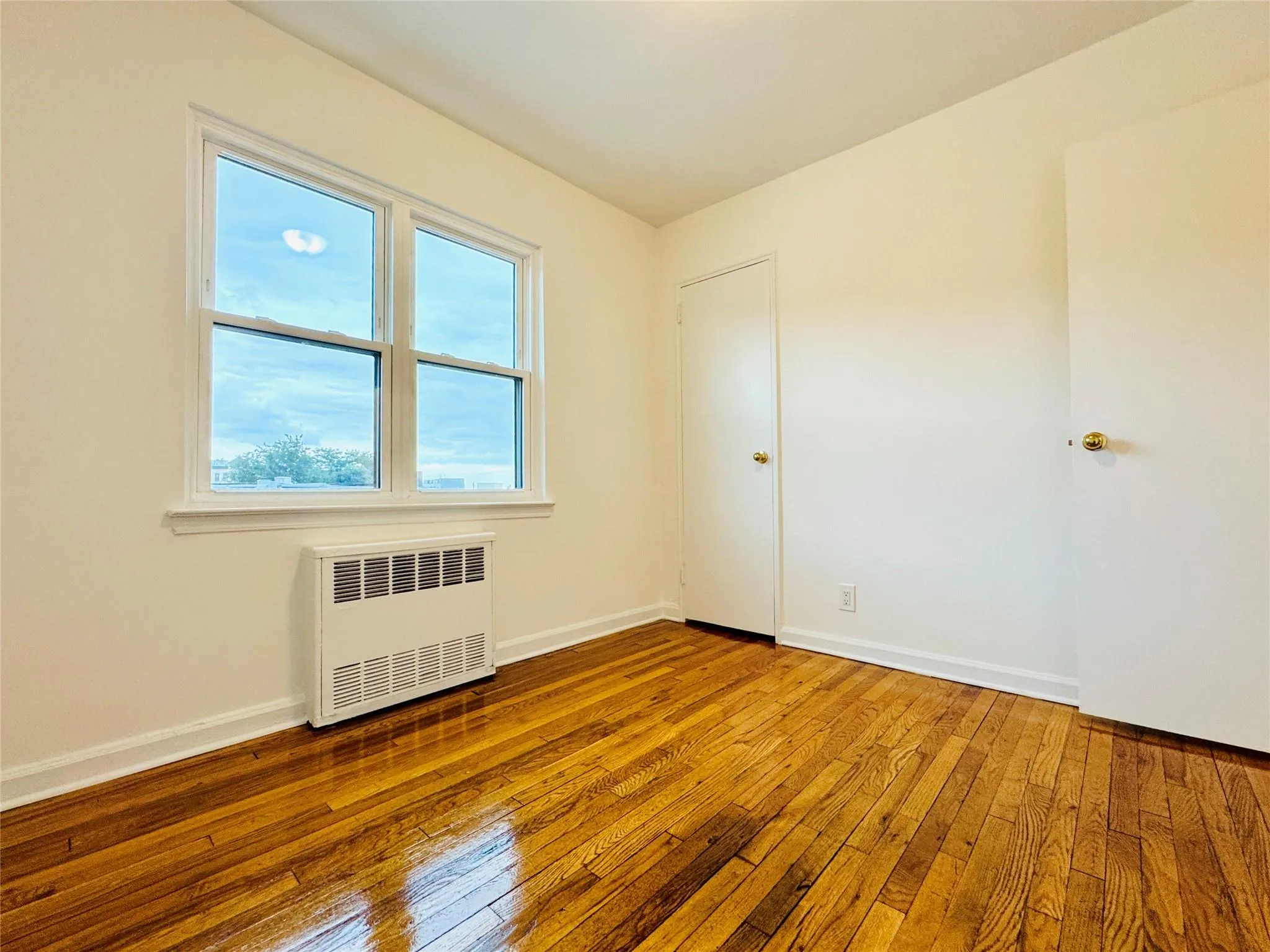 Spare room featuring wood-type flooring and radiator heating unit Spare room featuring wood-type flooring and radiator heating unit