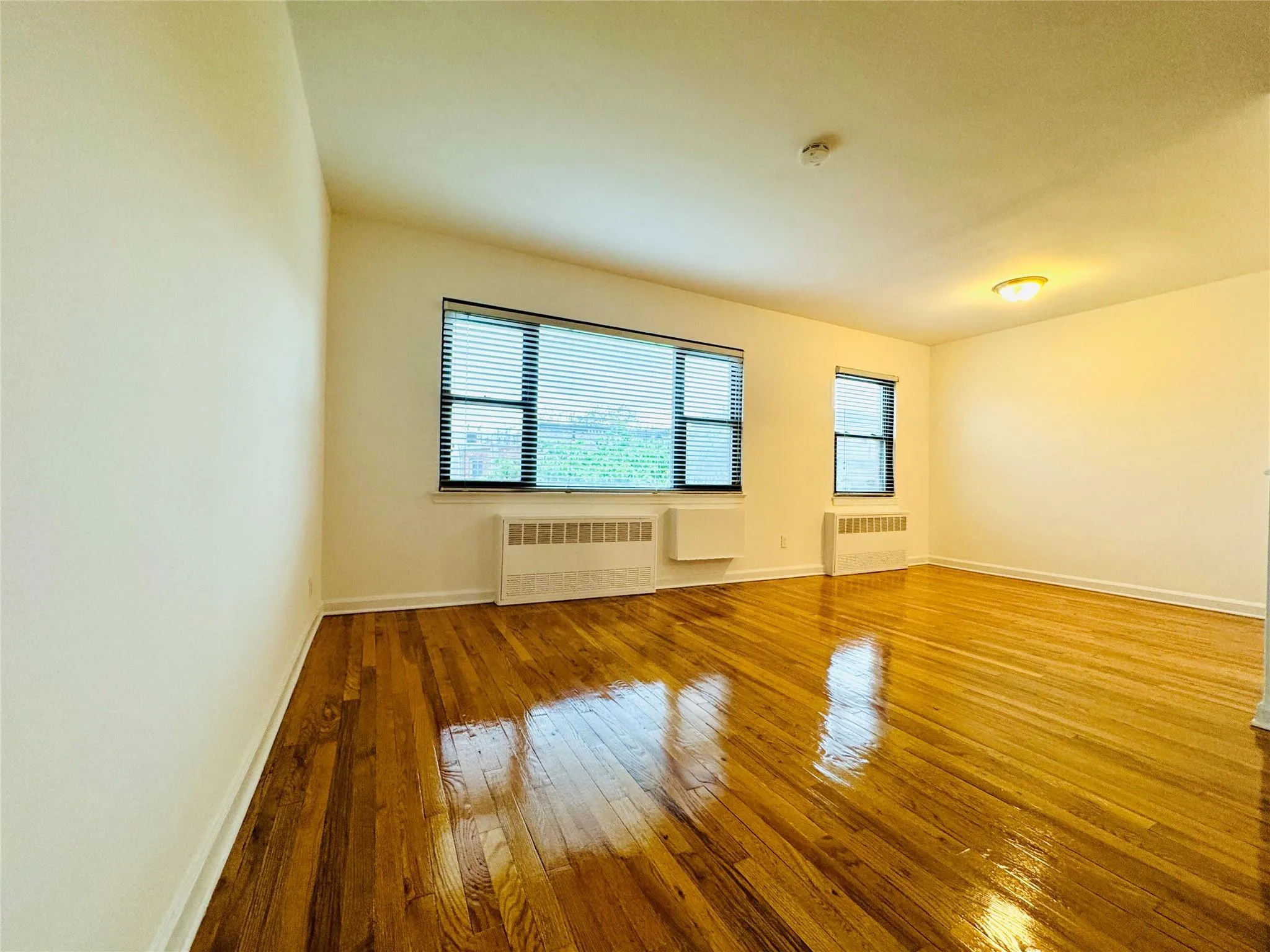 Empty room featuring radiator and hardwood / wood-style flooring Empty room featuring radiator and hardwood / wood-style flooring
