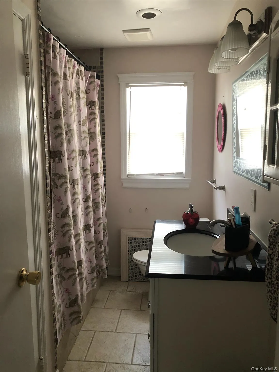 Bathroom with vanity, radiator, and stone tile floors Bathroom with vanity, radiator, and stone tile floors