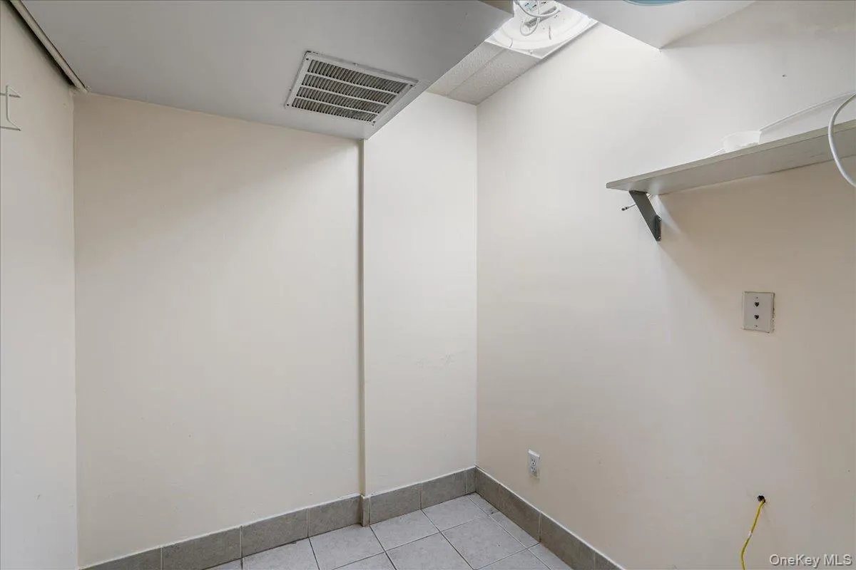 Laundry area with light tile patterned flooring and baseboards Laundry area with light tile patterned flooring and baseboards