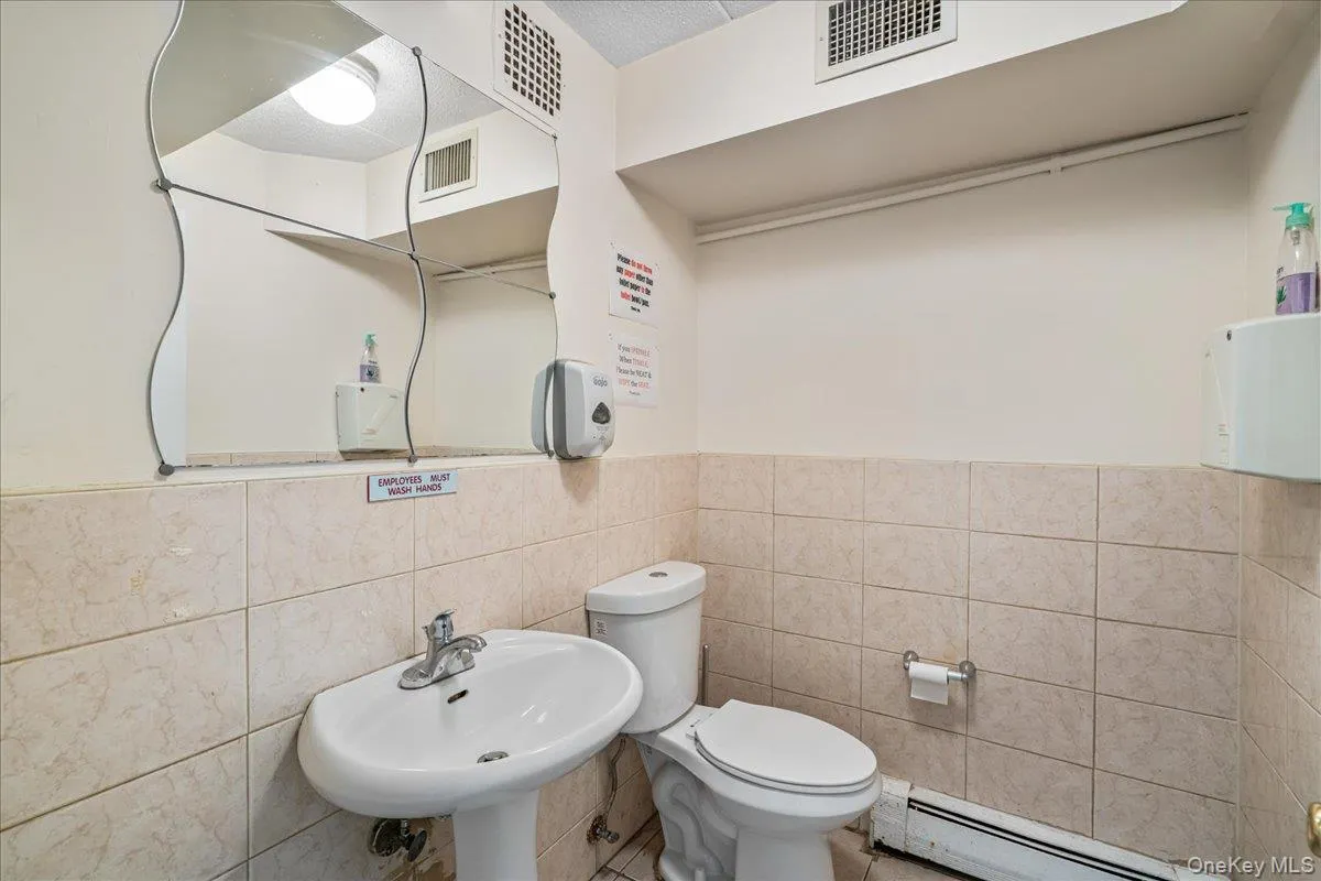 Bathroom featuring baseboard heating, tile walls, and a wainscoted wall Bathroom featuring baseboard heating, tile walls, and a wainscoted wall
