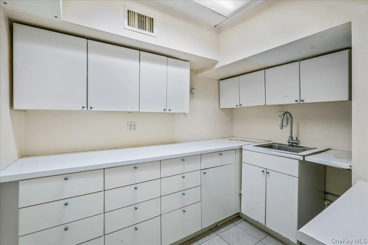 Kitchen featuring light countertops, white cabinets, and light tile patterned flooring Kitchen featuring light countertops, white cabinets, and light tile patterned flooring