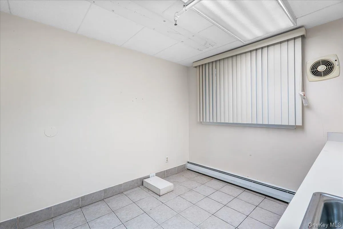 Unfurnished room with baseboard heating and tile patterned floors Unfurnished room with baseboard heating and tile patterned floors