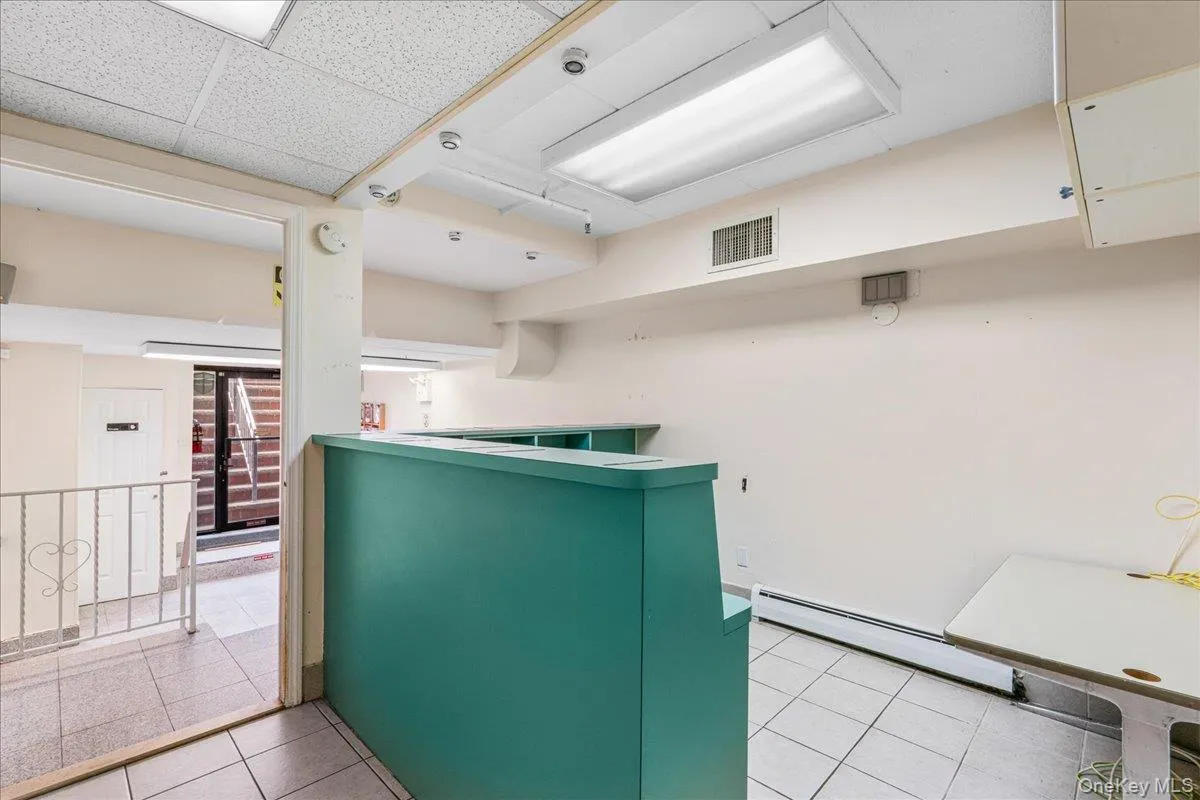 Kitchen with light tile patterned floors, baseboard heating, and a drop ceiling Kitchen with light tile patterned floors, baseboard heating, and a drop ceiling