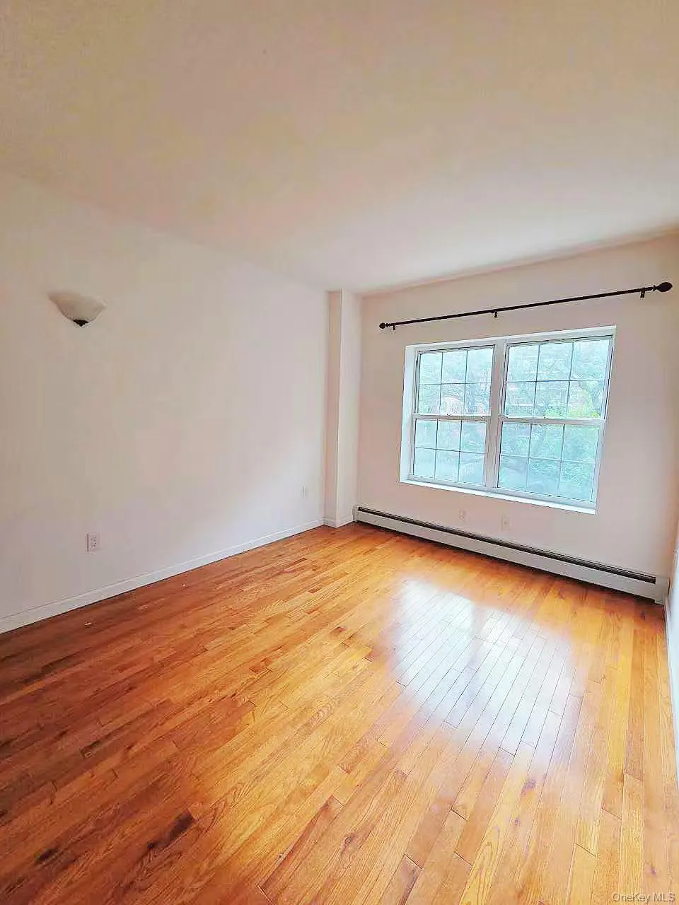 Empty room featuring a baseboard radiator and light wood-style floors Empty room featuring a baseboard radiator and light wood-style floors