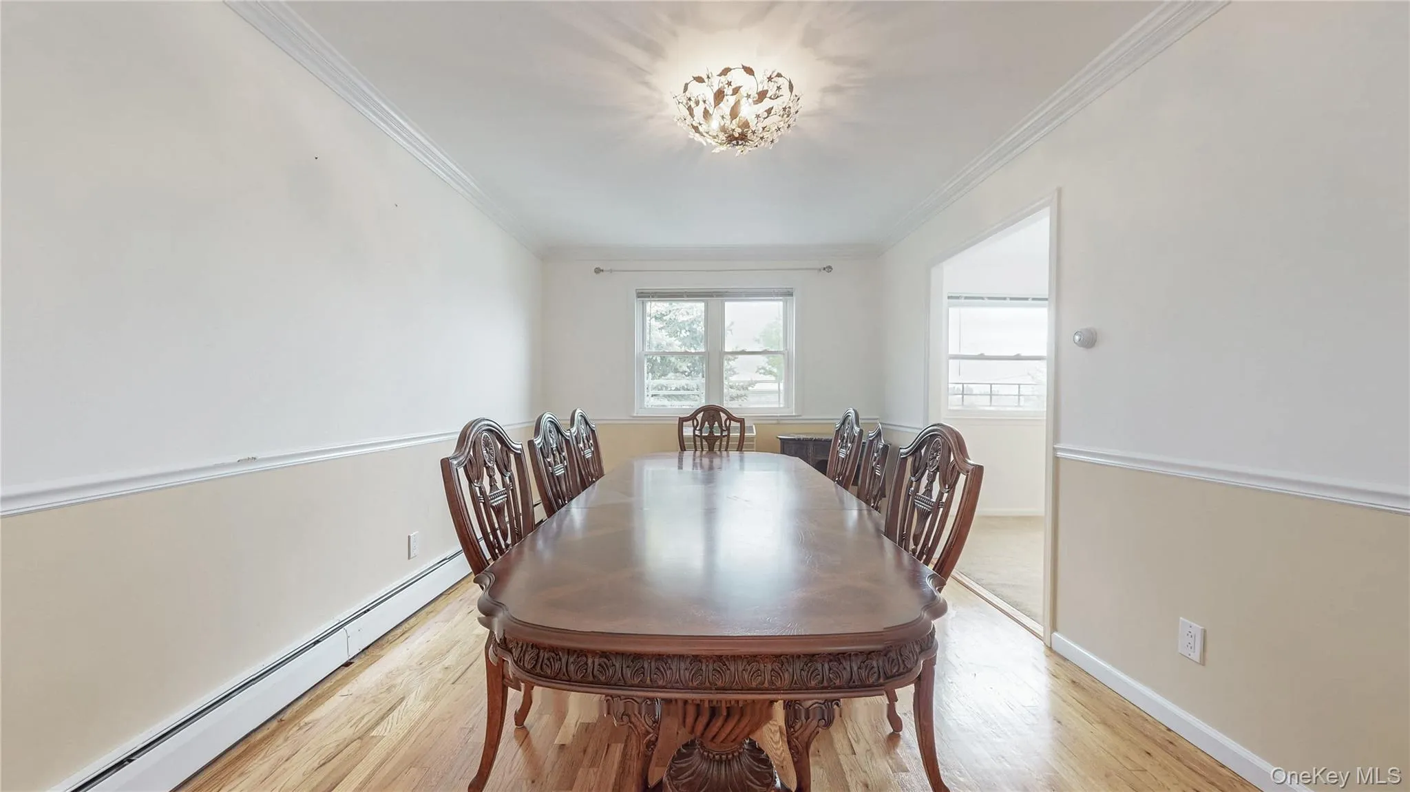 Dining space with baseboard heating, light wood-type flooring, and ornamental molding Dining space with baseboard heating, light wood-type flooring, and ornamental molding