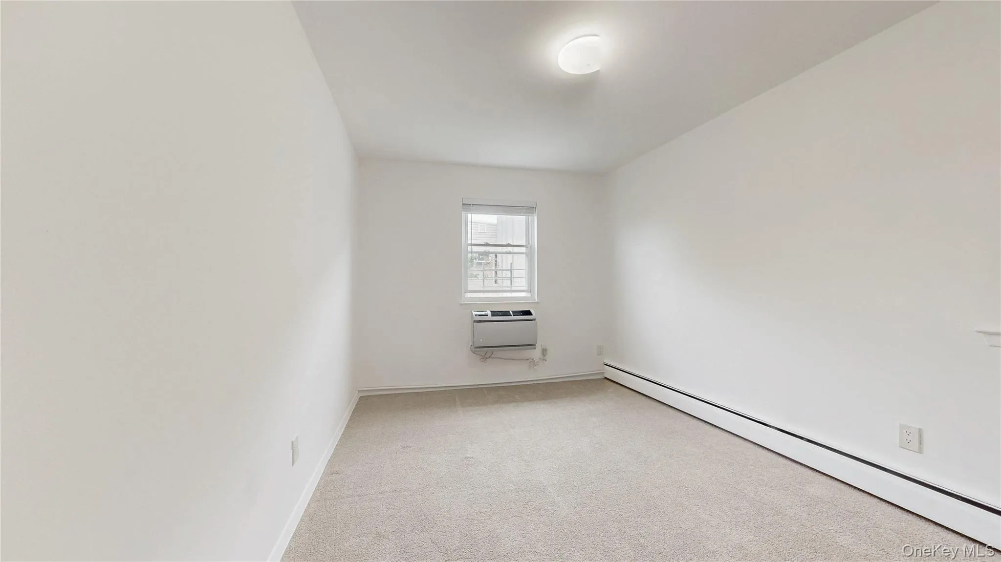 Unfurnished room with baseboard heating and light carpet Unfurnished room with baseboard heating and light carpet