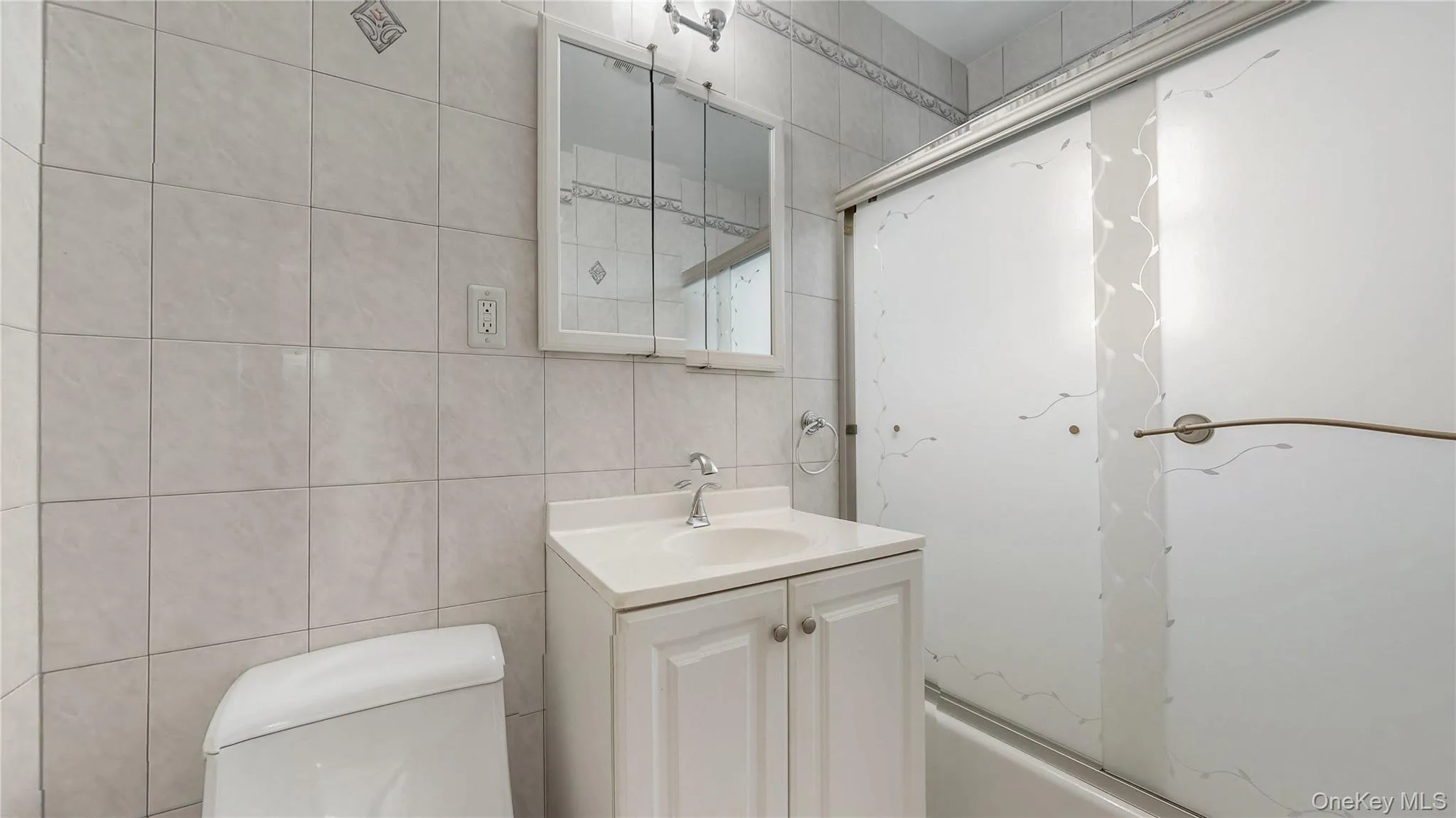 Full bathroom with tile walls, vanity, and tub / shower combination Full bathroom with tile walls, vanity, and tub / shower combination
