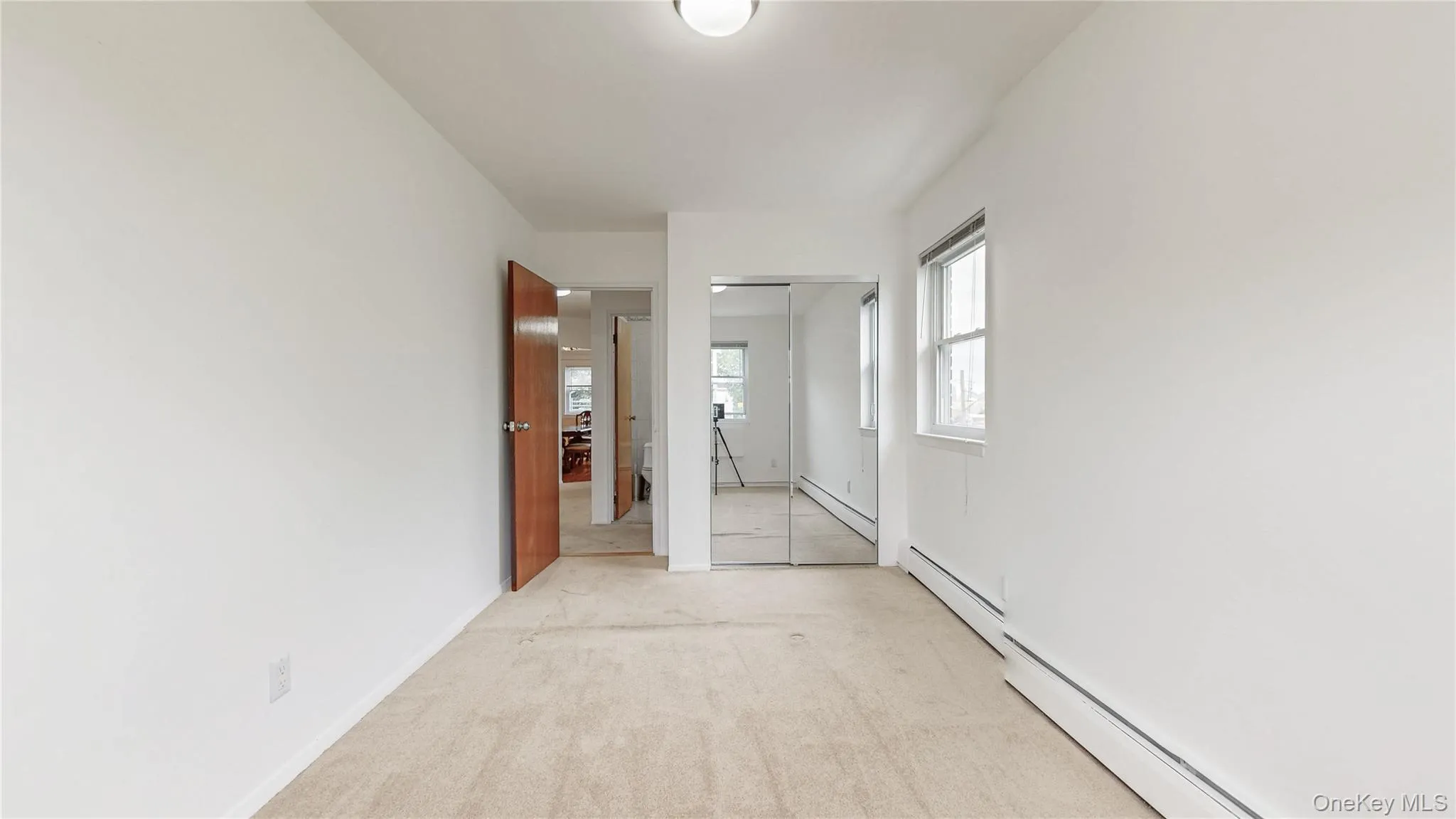 Hallway featuring light colored carpet and a baseboard radiator Hallway featuring light colored carpet and a baseboard radiator