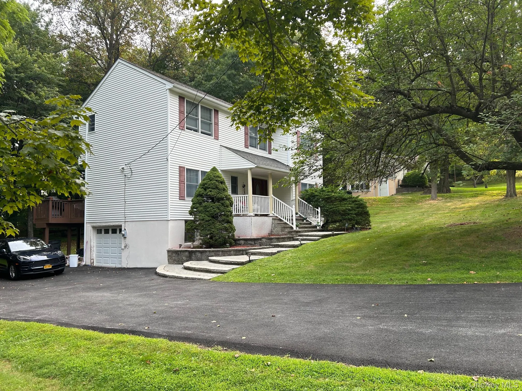 View of front of home with an attached garage, a porch, driveway, and a front yard View of front of home with an attached garage, a porch, driveway, and a front yard