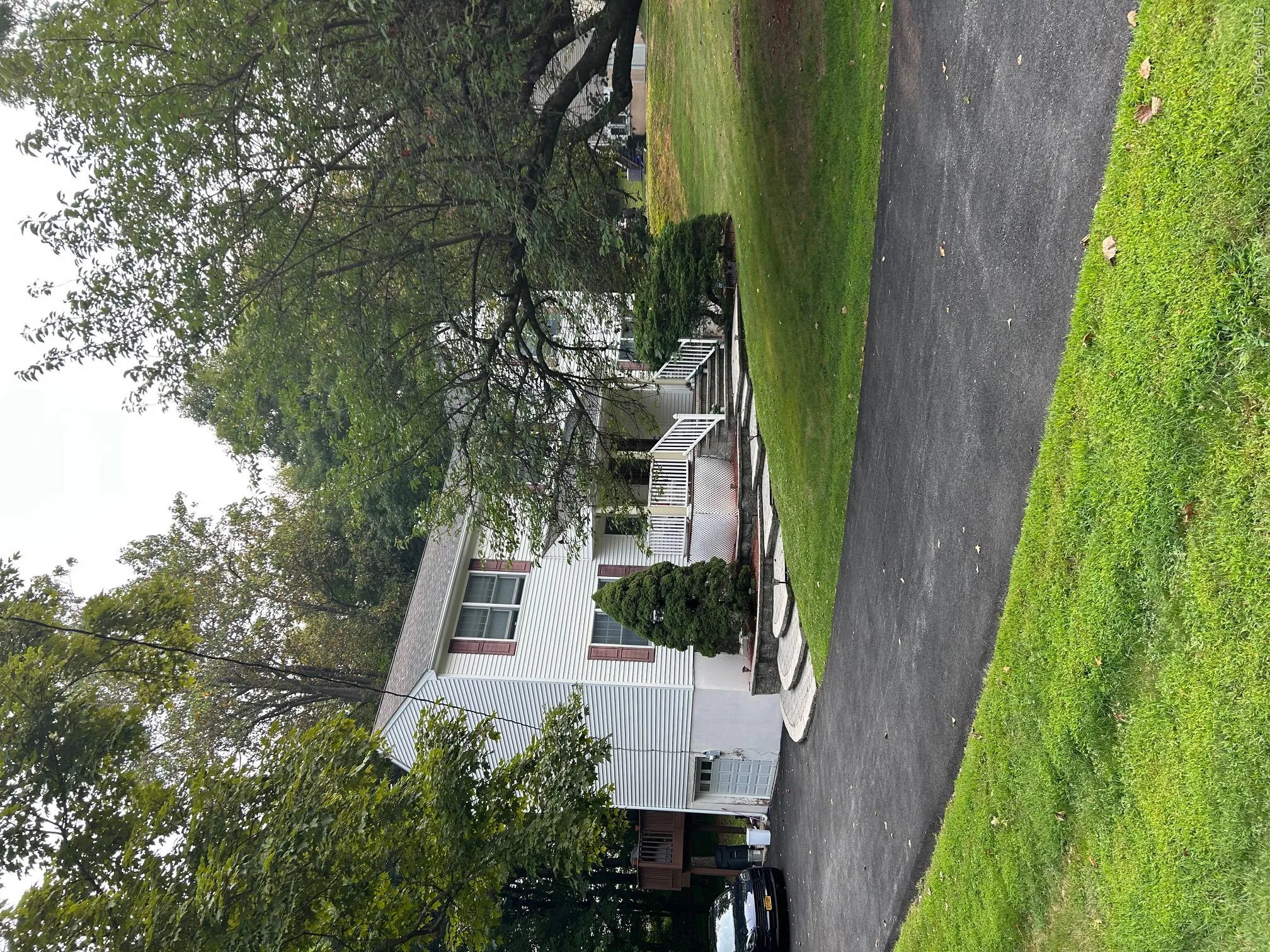 View of front of property featuring a garage, asphalt driveway, a front lawn, and a porch View of front of property featuring a garage, asphalt driveway, a front lawn, and a porch