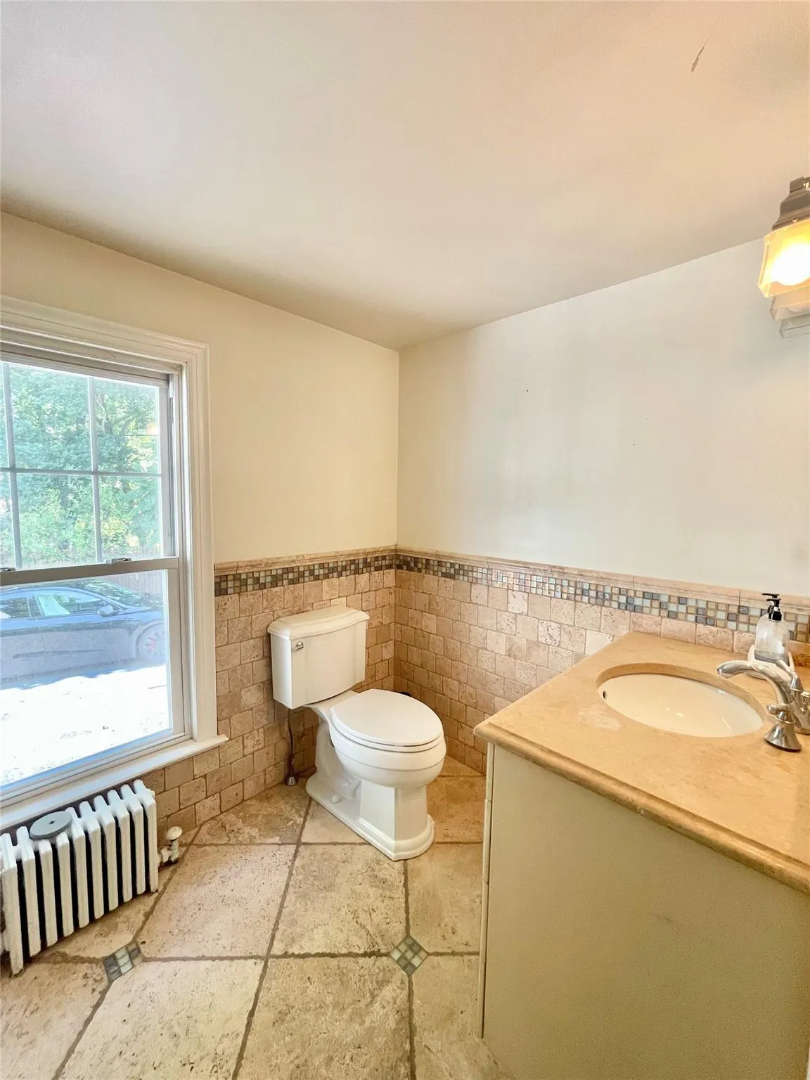 Half bath featuring a wainscoted wall, radiator heating unit, tile walls, and vanity Half bath featuring a wainscoted wall, radiator heating unit, tile walls, and vanity