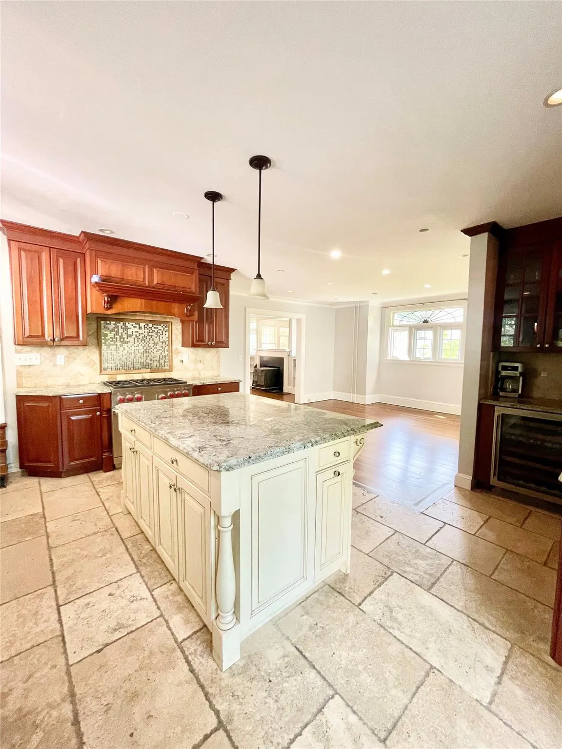 Kitchen with stone tile floors, a kitchen island, light stone counters, backsplash, and beverage cooler Kitchen with stone tile floors, a kitchen island, light stone counters, backsplash, and beverage cooler