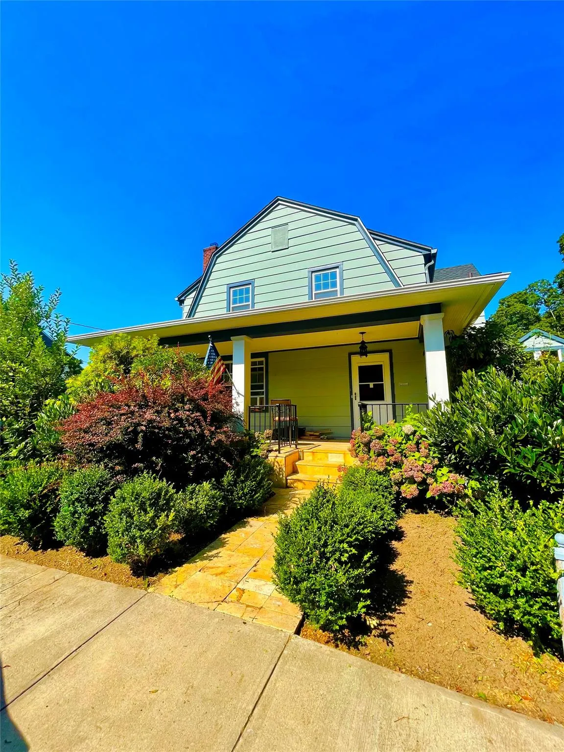 Colonial inspired home with a gambrel roof, covered porch, and a chimney Colonial inspired home with a gambrel roof, covered porch, and a chimney