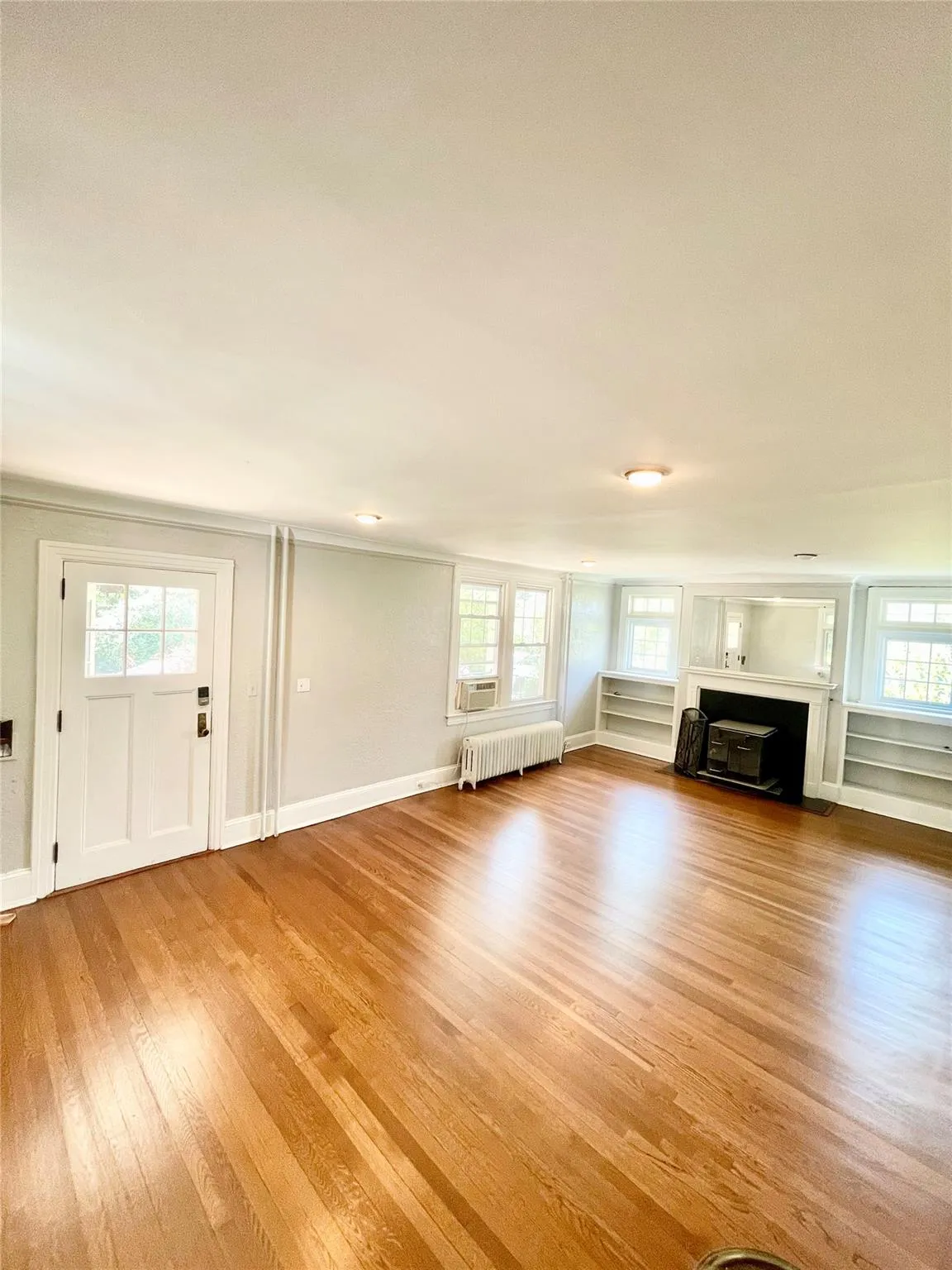 Unfurnished living room with light wood-type flooring, radiator heating unit, and crown molding Unfurnished living room with light wood-type flooring, radiator heating unit, and crown molding
