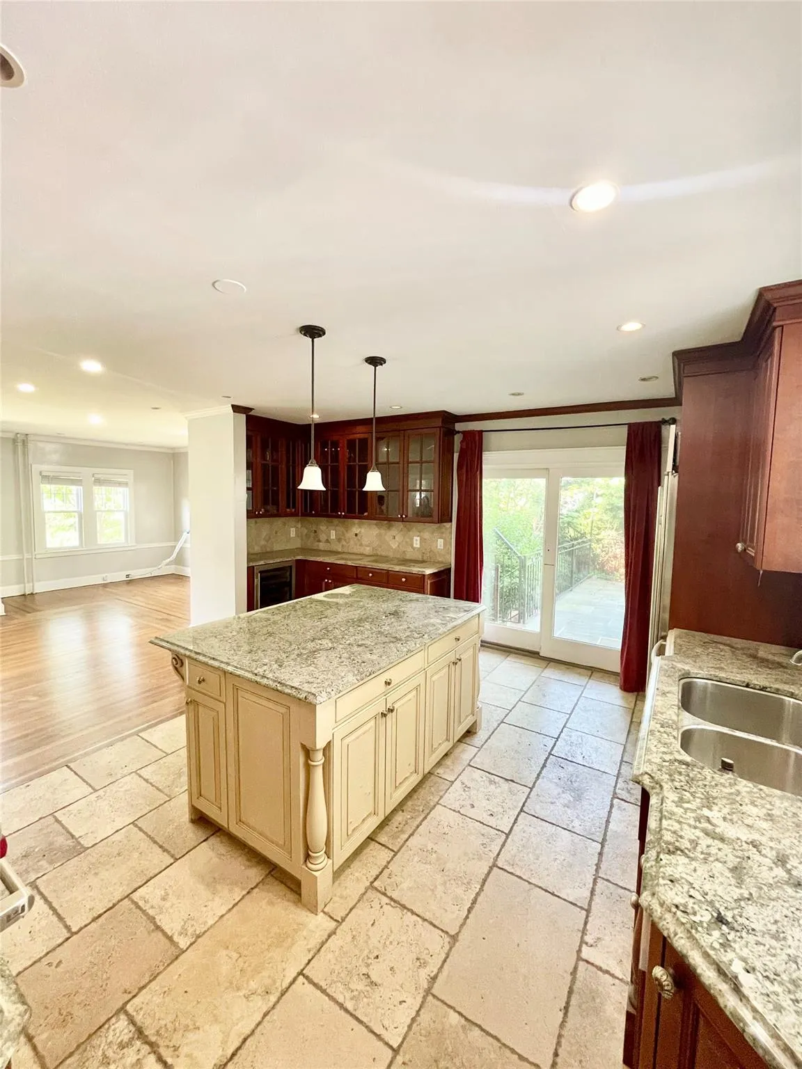 Kitchen featuring cream cabinetry, stone tile flooring, decorative backsplash, recessed lighting, and glass insert cabinets Kitchen featuring cream cabinetry, stone tile flooring, decorative backsplash, recessed lighting, and glass insert cabinets