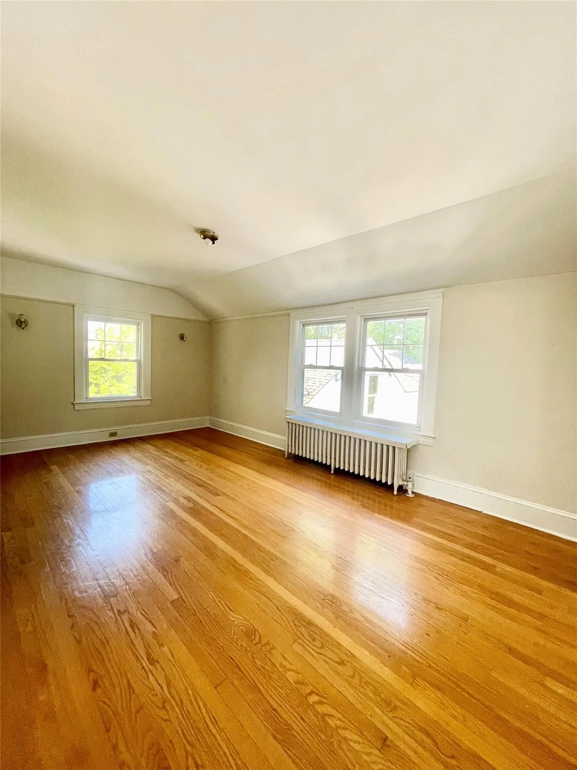 Bonus room with wood finished floors, radiator, and vaulted ceiling Bonus room with wood finished floors, radiator, and vaulted ceiling