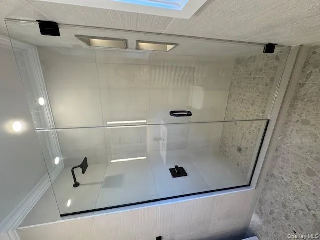 Bathroom with crown molding, a stall shower, and tile walls Bathroom with crown molding, a stall shower, and tile walls