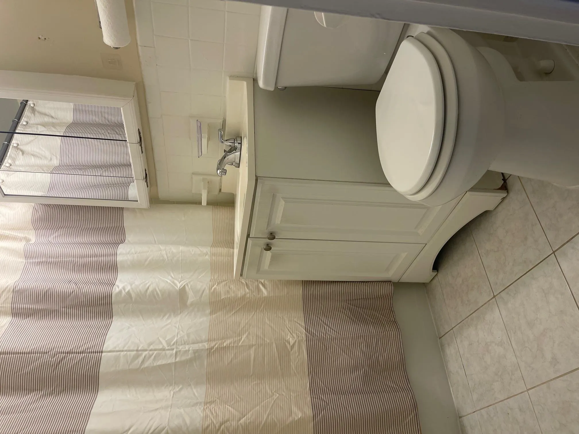 Full bathroom with tile walls, vanity, tile patterned floors, and shower / bath combo with shower curtain Full bathroom with tile walls, vanity, tile patterned floors, and shower / bath combo with shower curtain