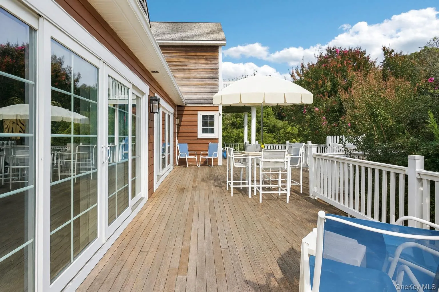 Expansive mahogany deck featuring an inviting outdoor dining area with seamless access through sliding glass doors. Expansive mahogany deck featuring an inviting outdoor dining area with seamless access through sliding glass doors.