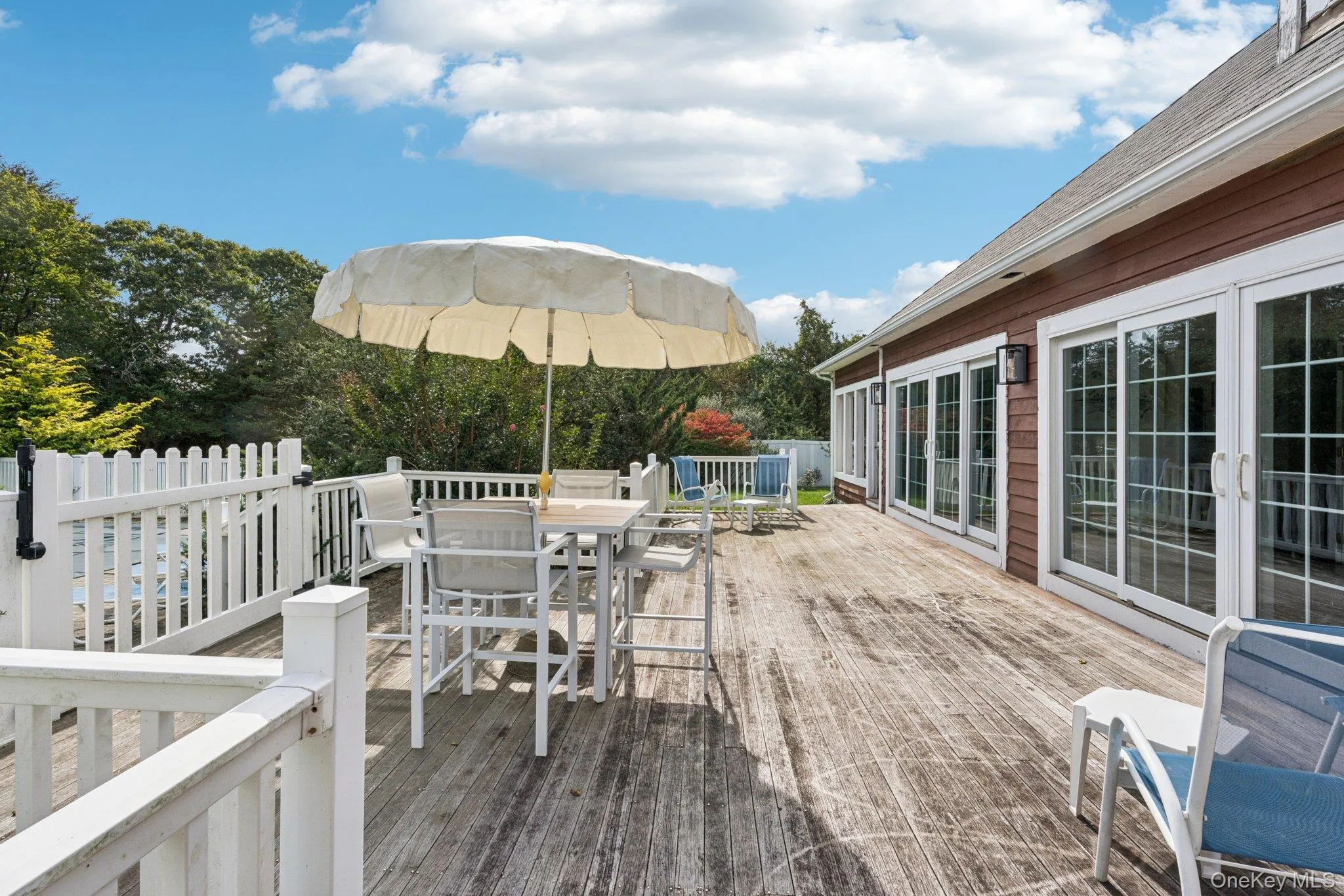 A beautifully crafted mahogany deck designed for outdoor dining and entertaining, accessible through elegant sliding glass doors. A beautifully crafted mahogany deck designed for outdoor dining and entertaining, accessible through elegant sliding glass doors.