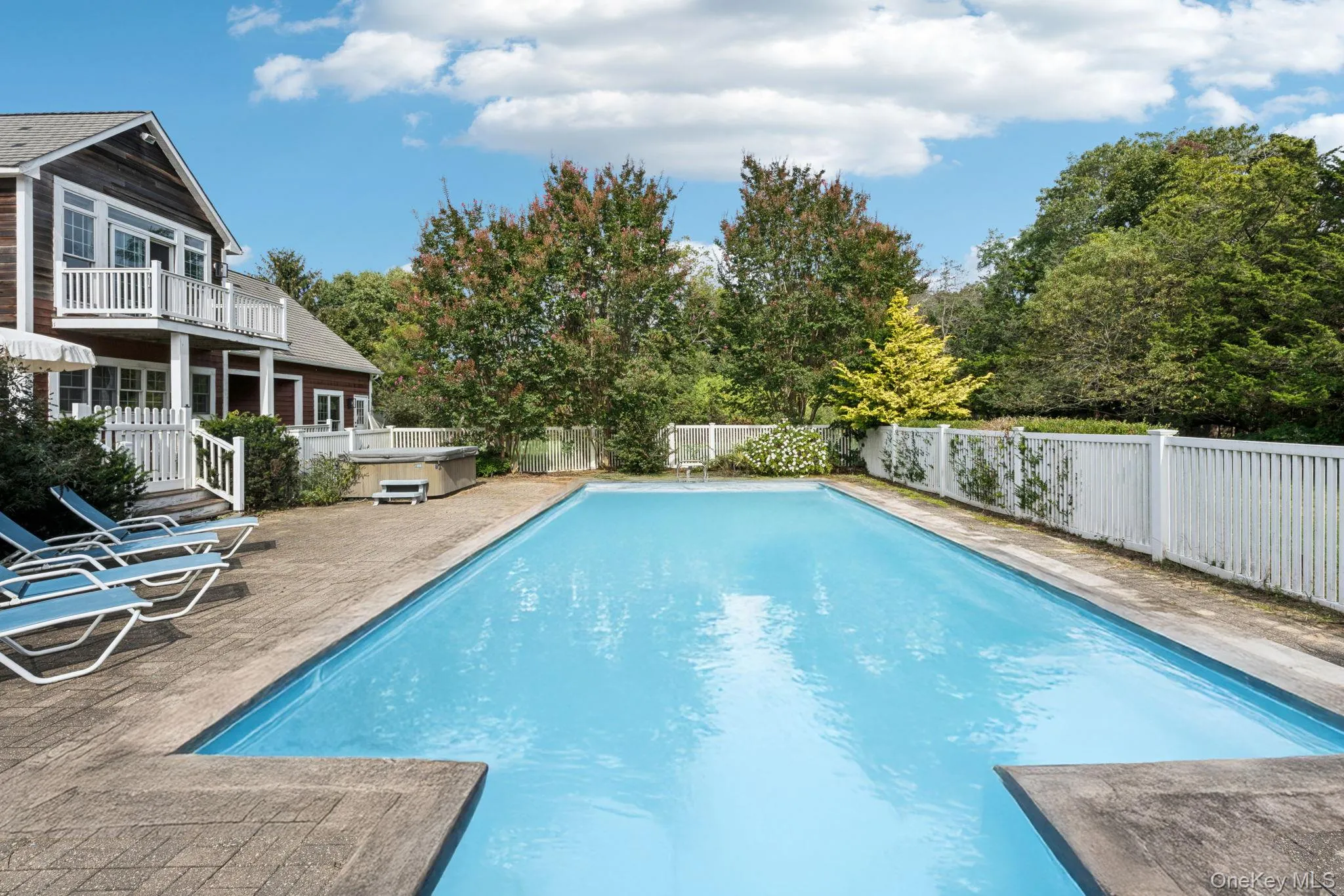 A captivating view reveals the swimming pool, sunlit patio, and spa, all surrounded by a private fenced backyard and complemented by a balcony that overlooks this serene outdoor haven. A captivating view reveals the swimming pool, sunlit patio, and spa, all surrounded by a private fenced backyard and complemented by a balcony that overlooks this serene outdoor haven.