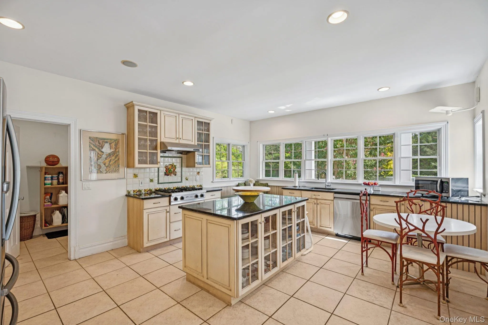 A beautifully appointed kitchen adorned with granite countertops, a central island, custom cabinetry with glass inserts, and an inviting eat-in area. A beautifully appointed kitchen adorned with granite countertops, a central island, custom cabinetry with glass inserts, and an inviting eat-in area.