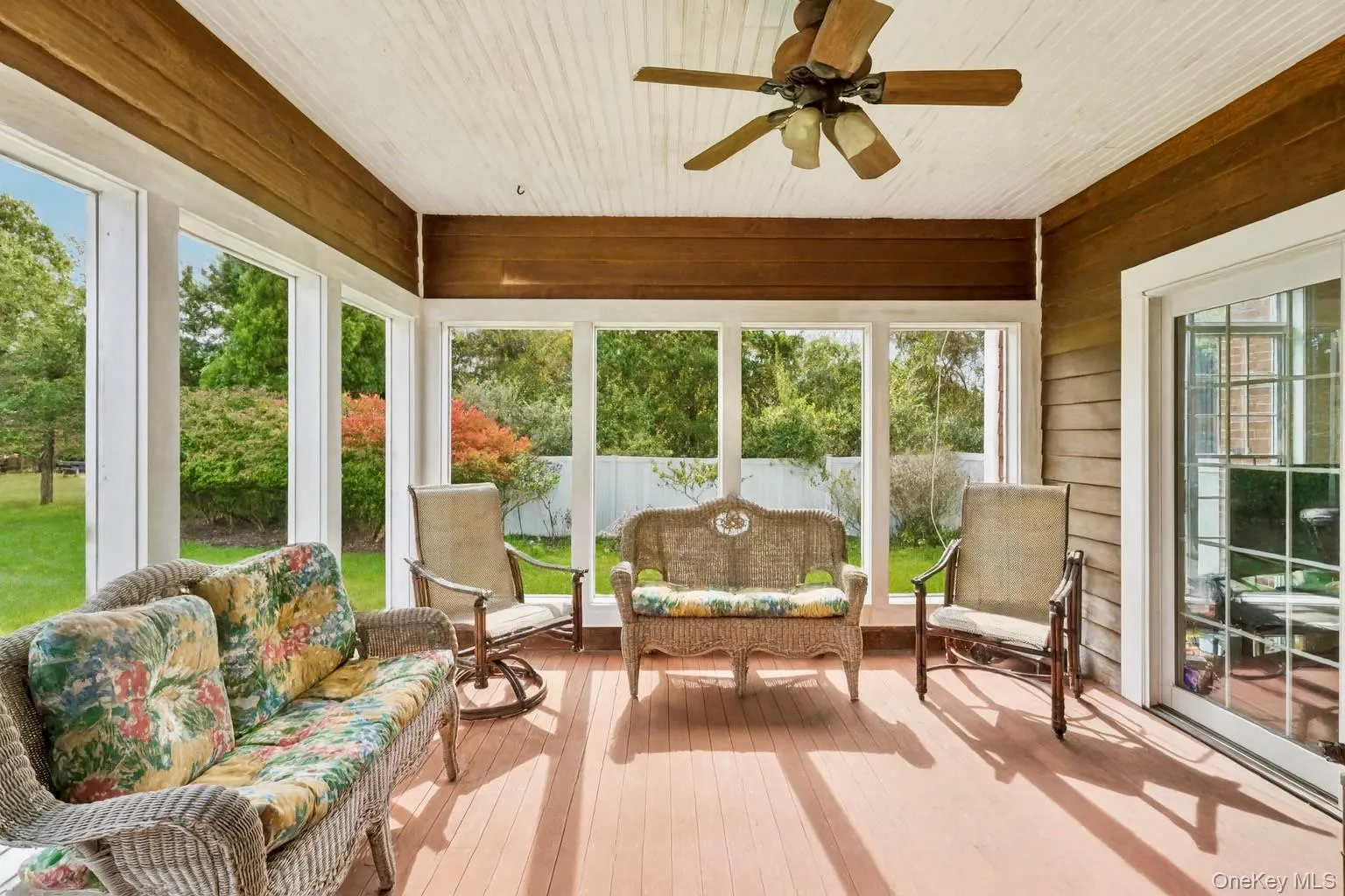 Sunroom featuring a ceiling fan, mahogany wood walls, and a warm, inviting ambiance. Sunroom featuring a ceiling fan, mahogany wood walls, and a warm, inviting ambiance.